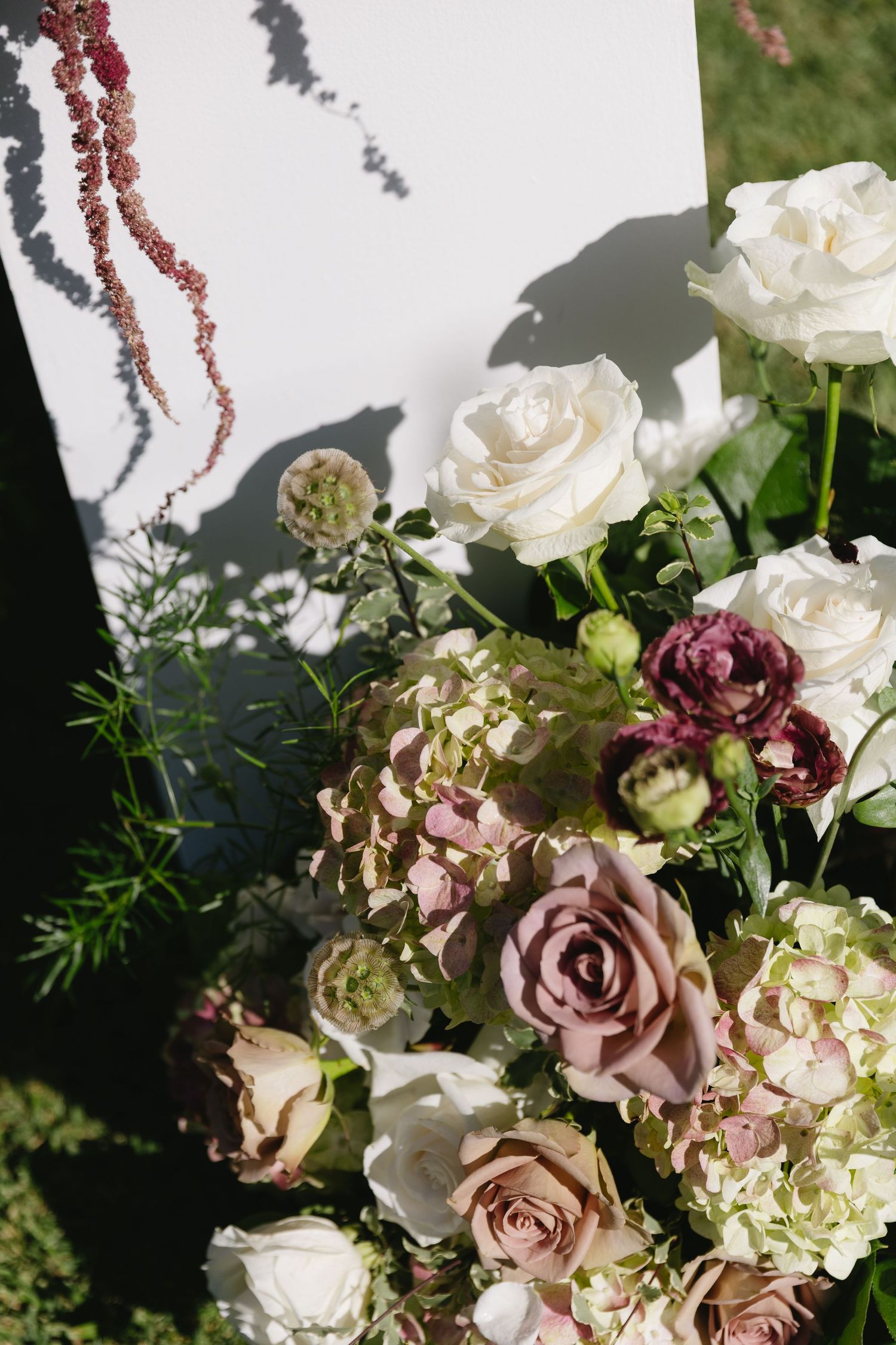 Elegant wedding bouquet with white roses and mauve flowers in natural lighting.