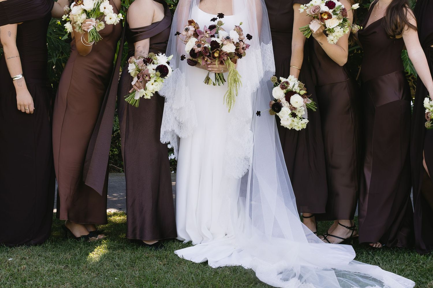Wedding party poses in formal attire with burgundy bridesmaid dresses.