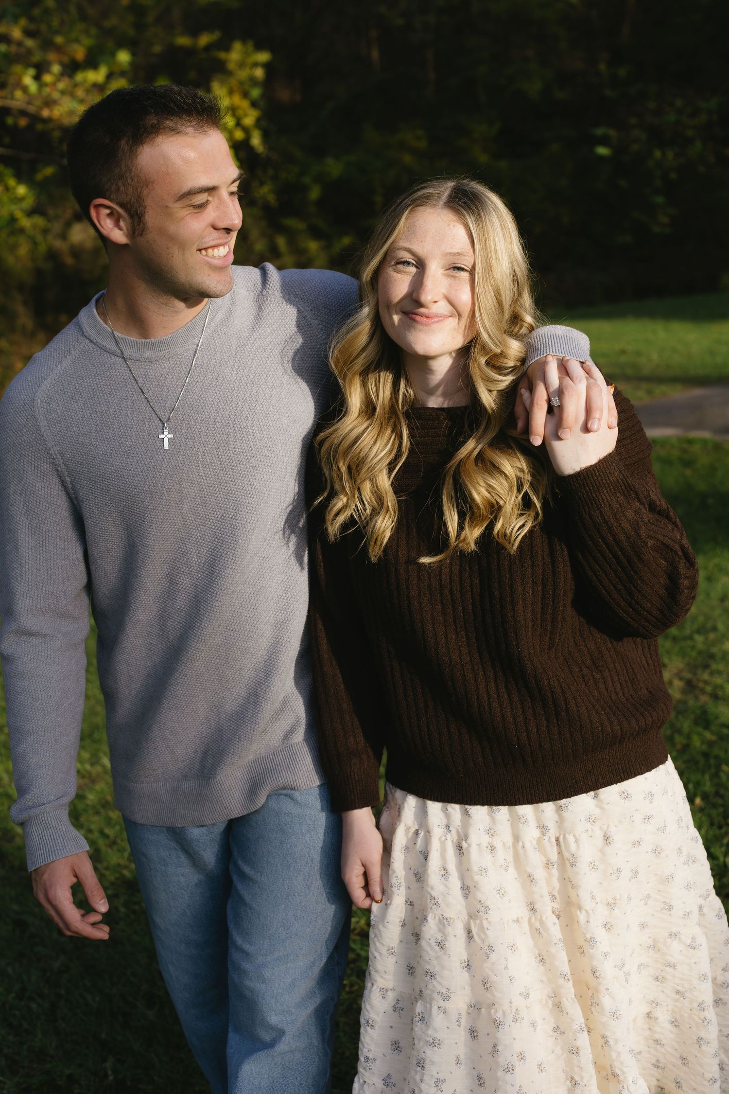 Couple in casual attire sharing tender moments against fall foliage.