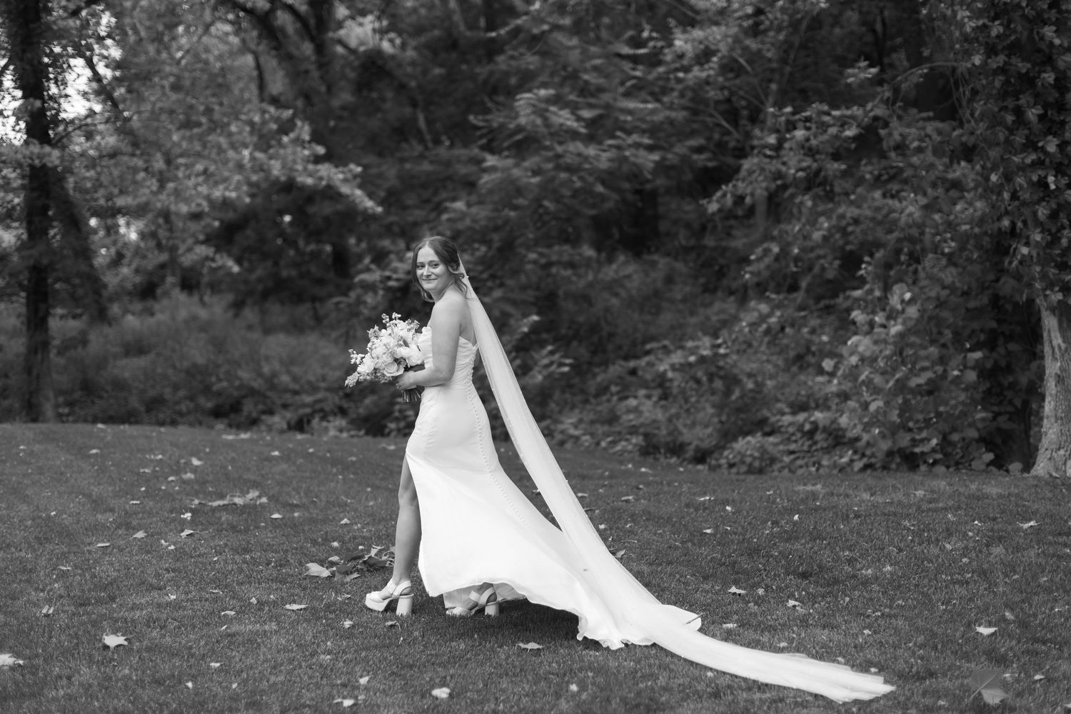 Outdoor garden wedding ceremony setup with white floral arrangements and natural greenery.