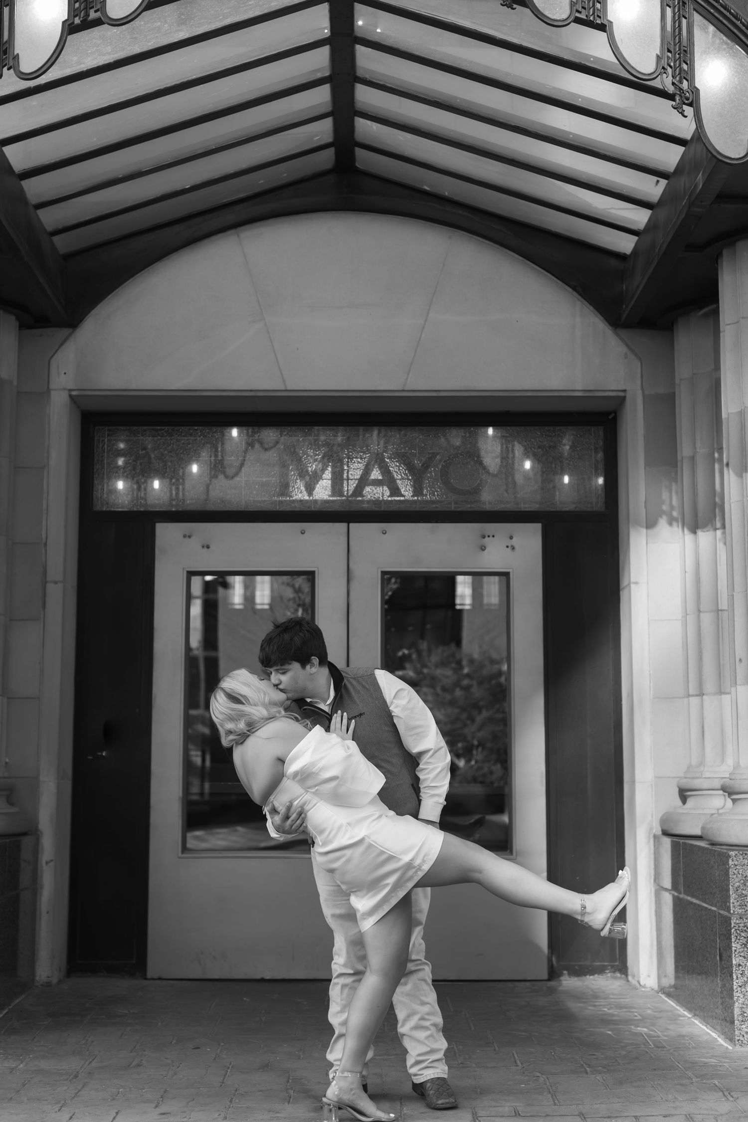 People dancing and posing together in creative poses against a brightly lit shopping center storefront.