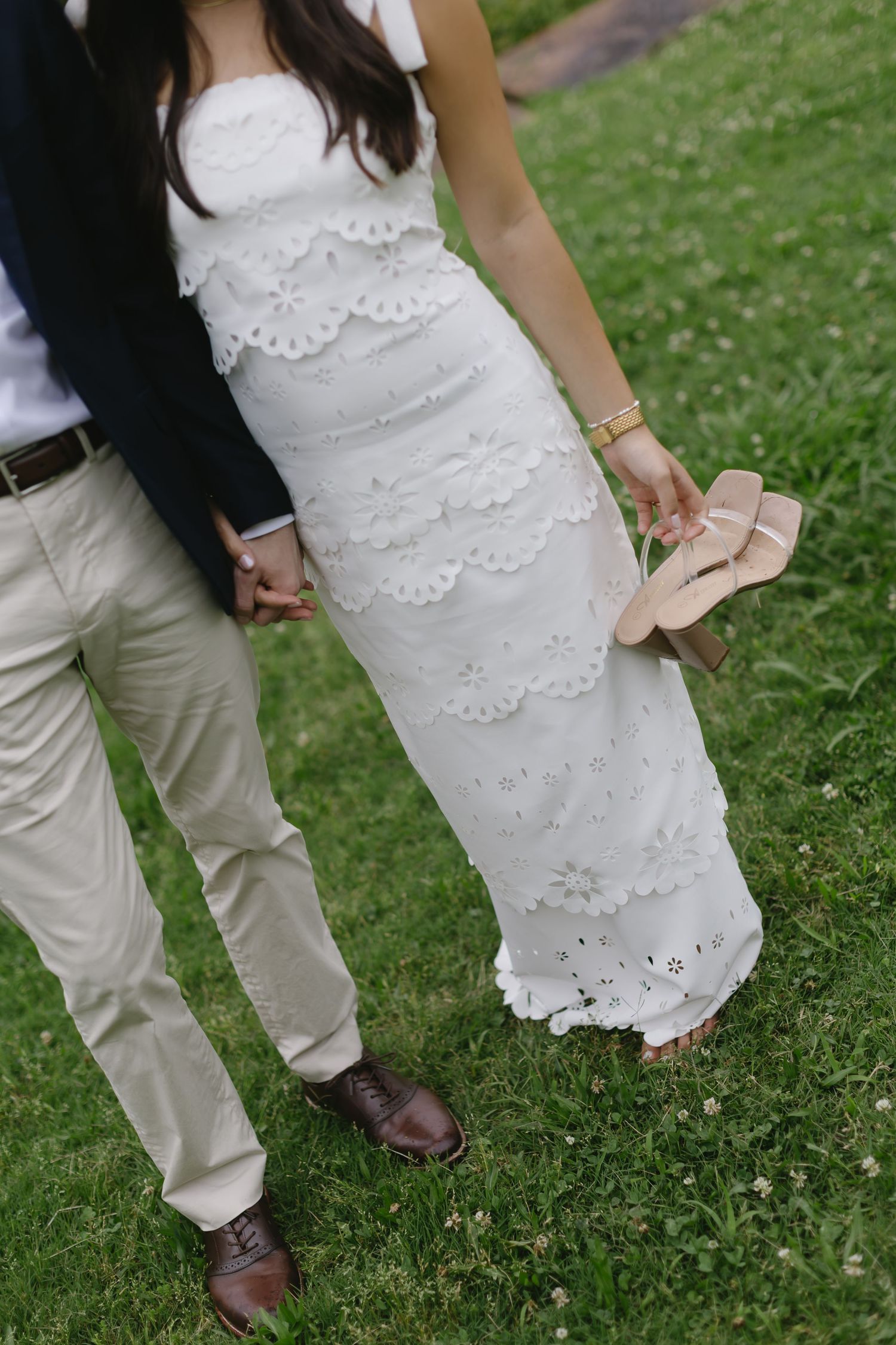 Candid wedding photography showing dress details and footwear on a grassy lawn.