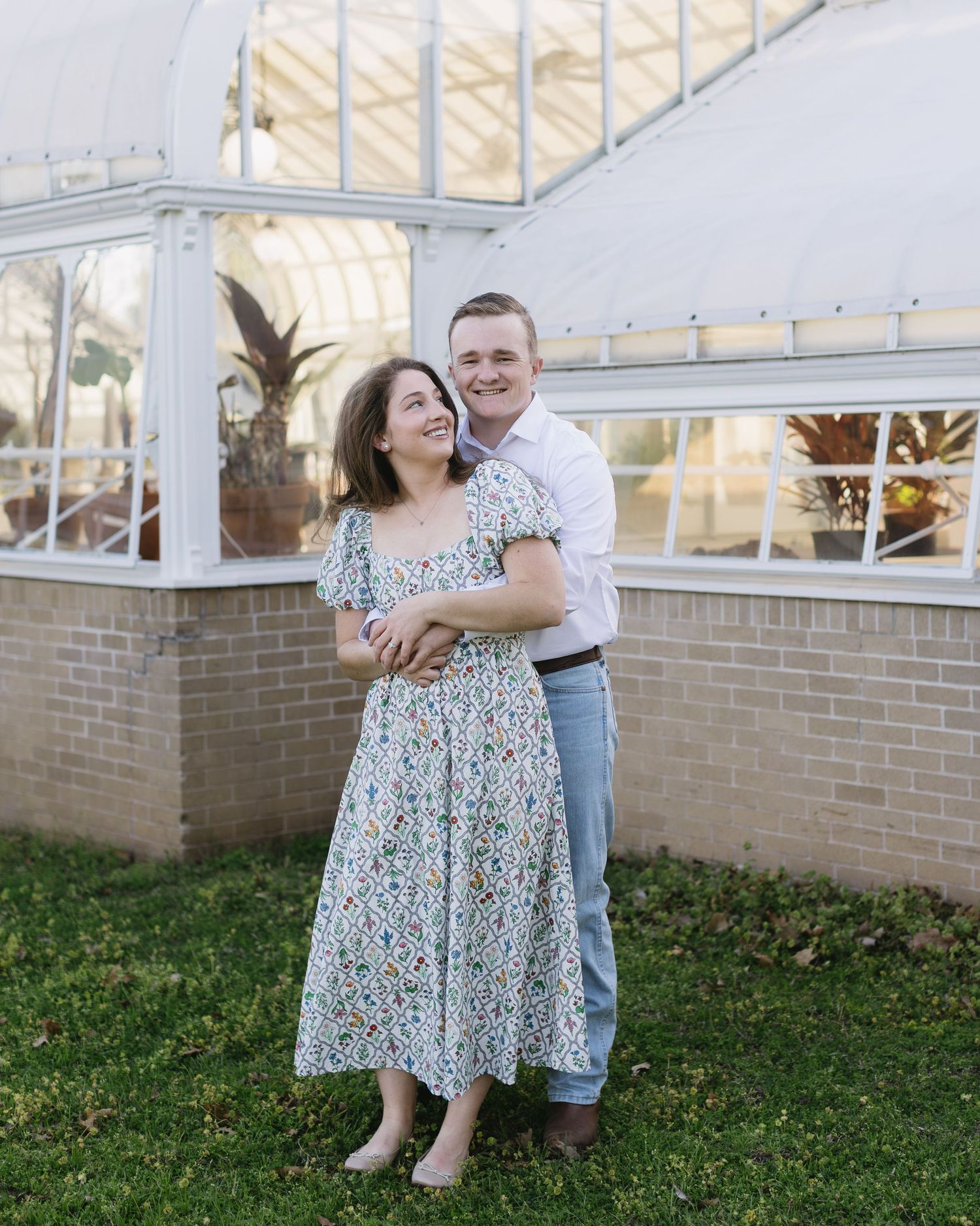 A romantic outdoor portrait session captured against a brick wall and garden setting at golden hour.