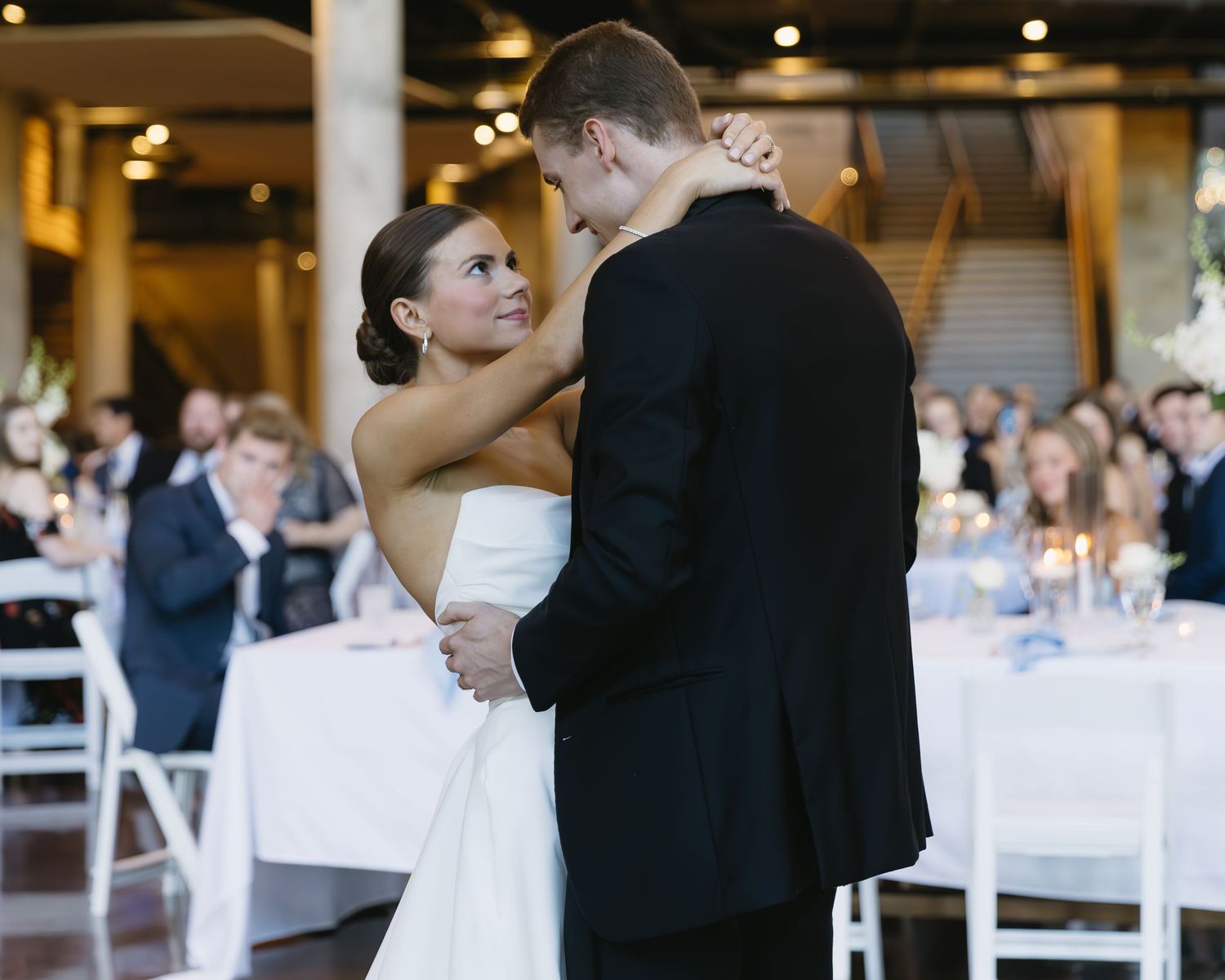 Wedding reception venue with white tablecloths and ambient lighting.