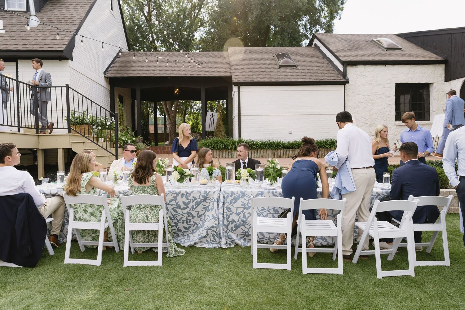 White folding chairs set up in rows on a lawn for an outdoor wedding ceremony.
