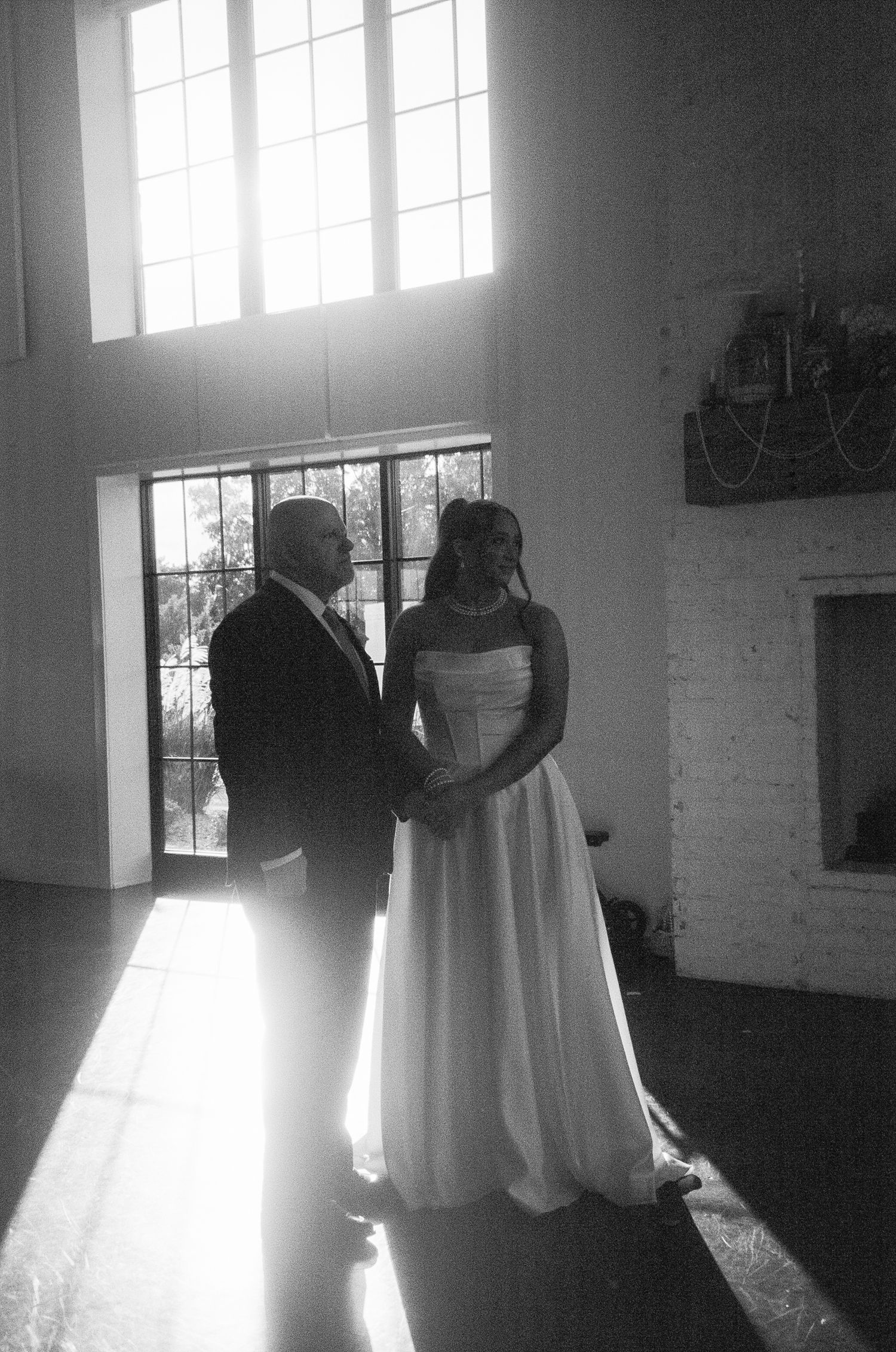 Dramatic black and white wedding photos silhouetted against bright sunlit windows.