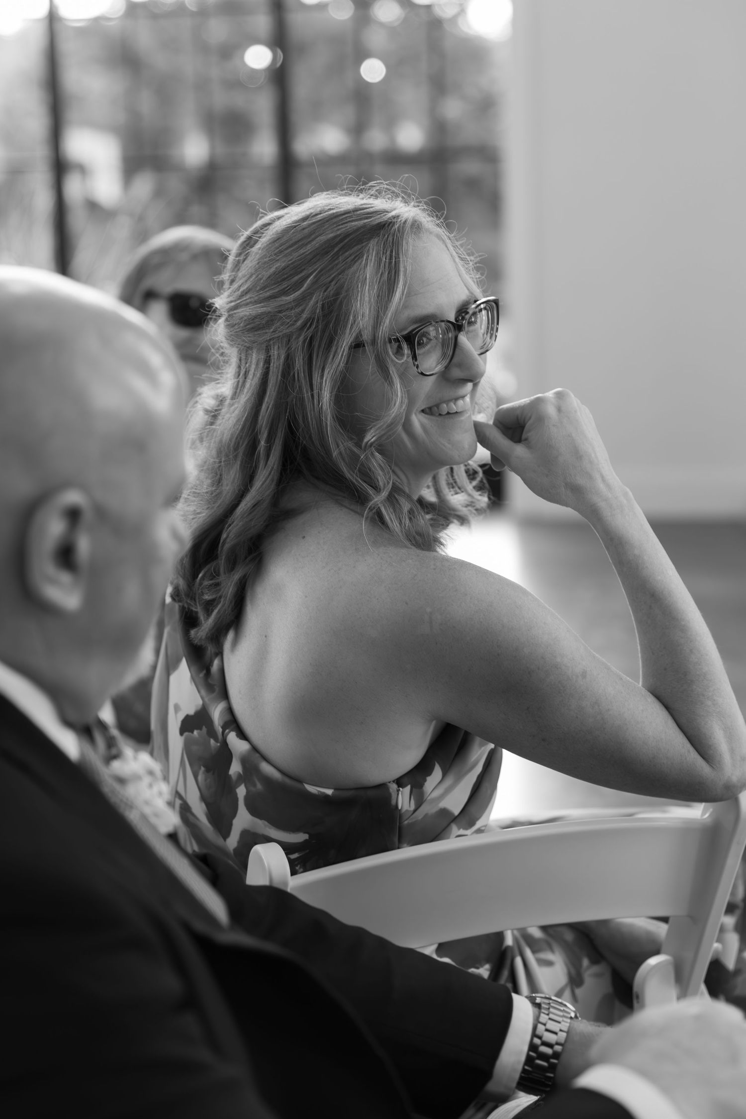 Black and white candid shot of wedding guests watching ceremony.