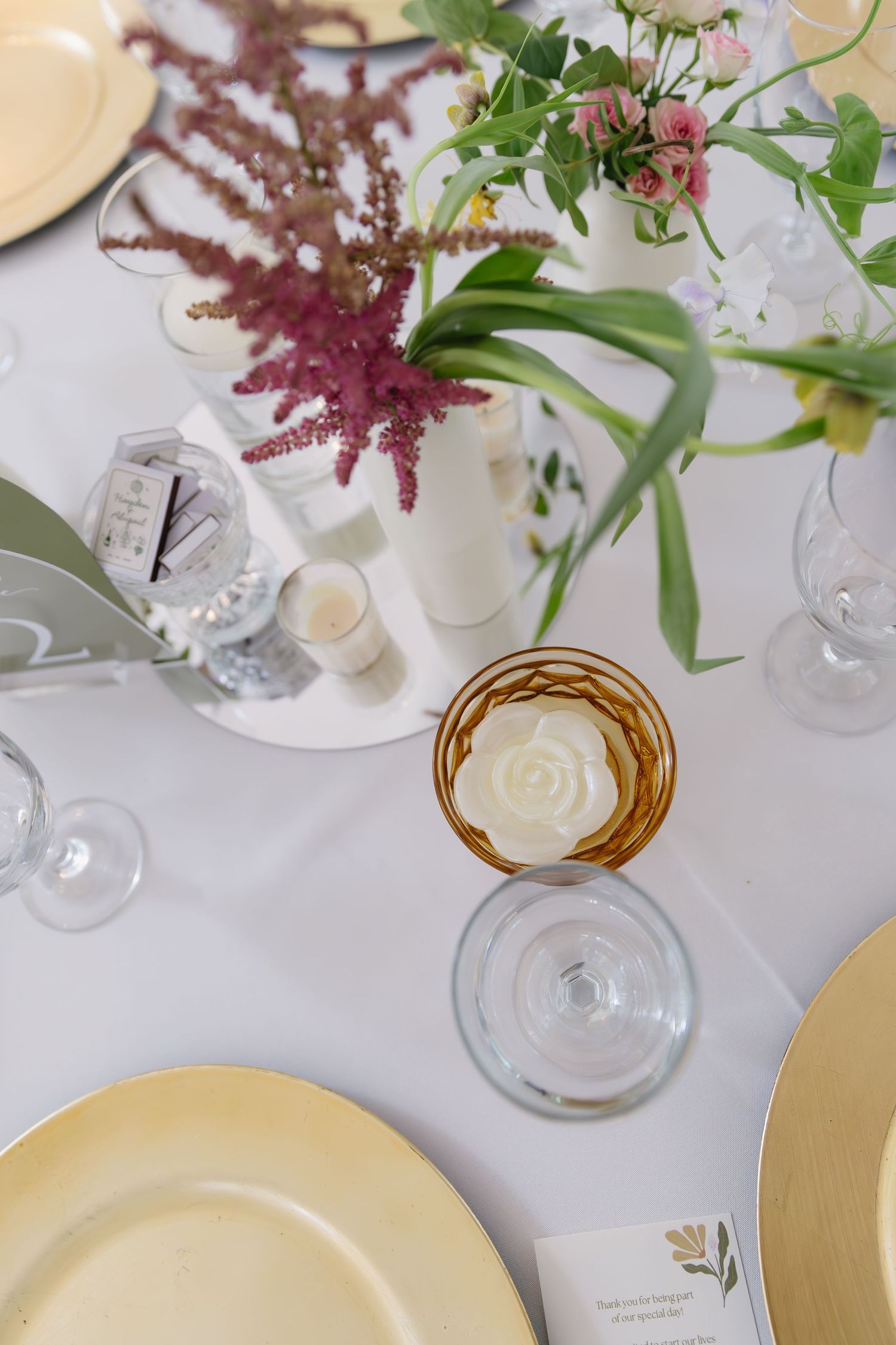 Wedding table setting with pink astilbe flowers and gold-rimmed plates.