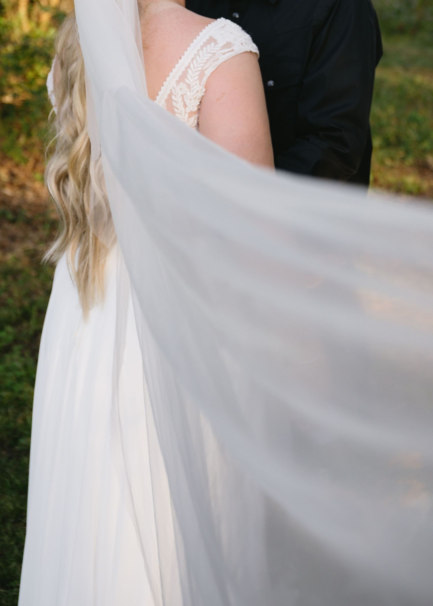 Flowing white wedding veil caught in gentle breeze during an outdoor photo session.