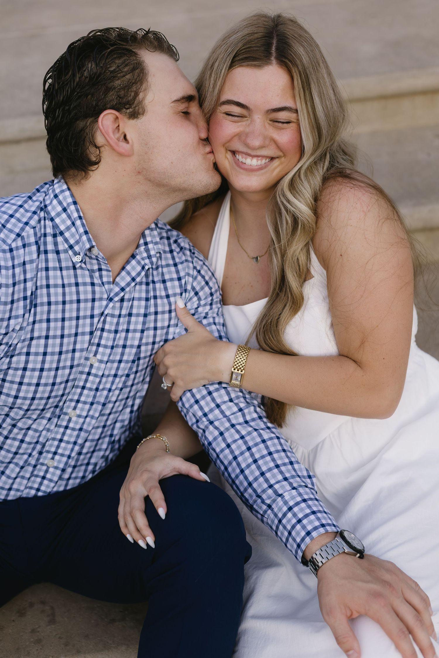 Romantic couple sharing sweet candid moments while sitting together wearing blue plaid and white outfits.