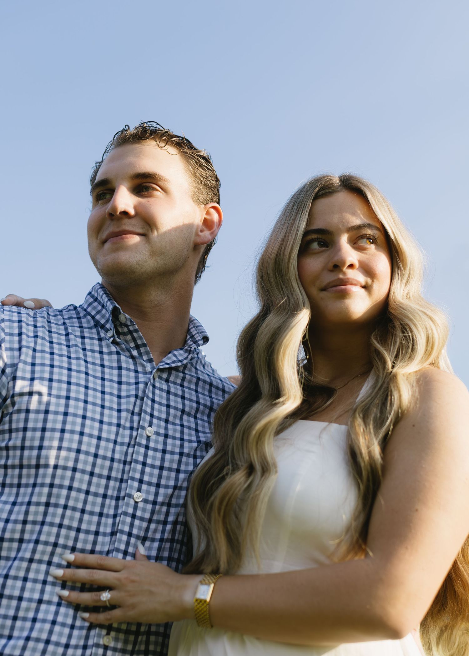 A couple sharing a joyful moment together outdoors in warm sunlight, showing affection in their casual attire.