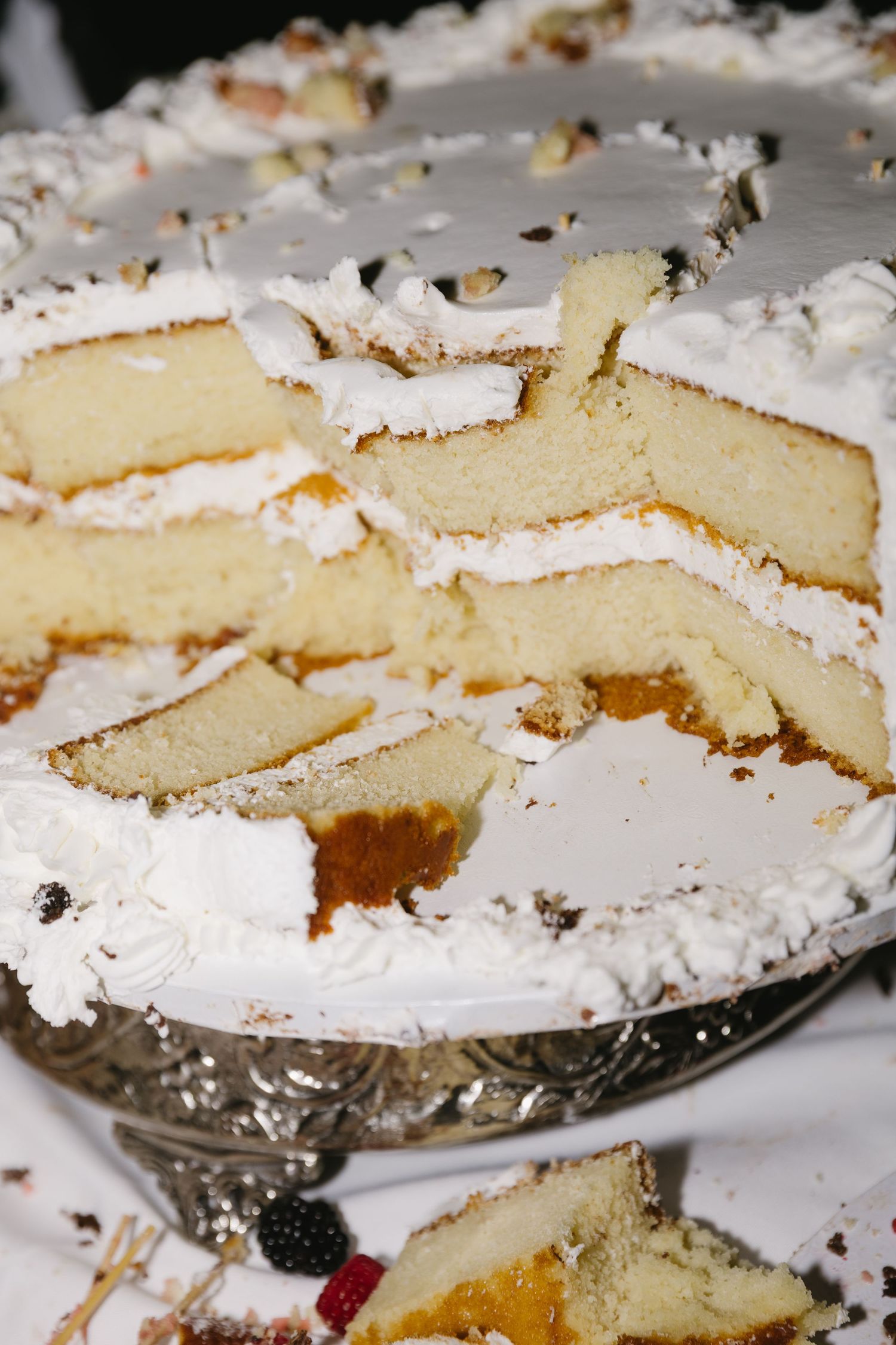 Sliced wedding cake with white frosting reveals layers of vanilla cake inside.