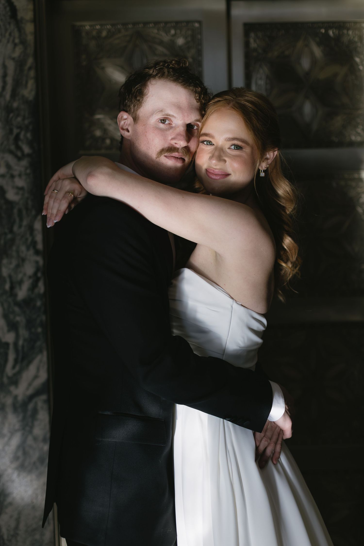 A tender embrace between newlyweds in classic black and white wedding attire.