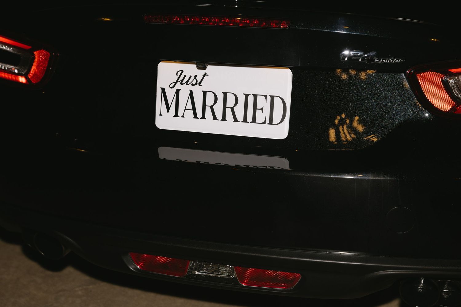 Car decorated with 'Just Married' sign photographed at night after wedding celebration.