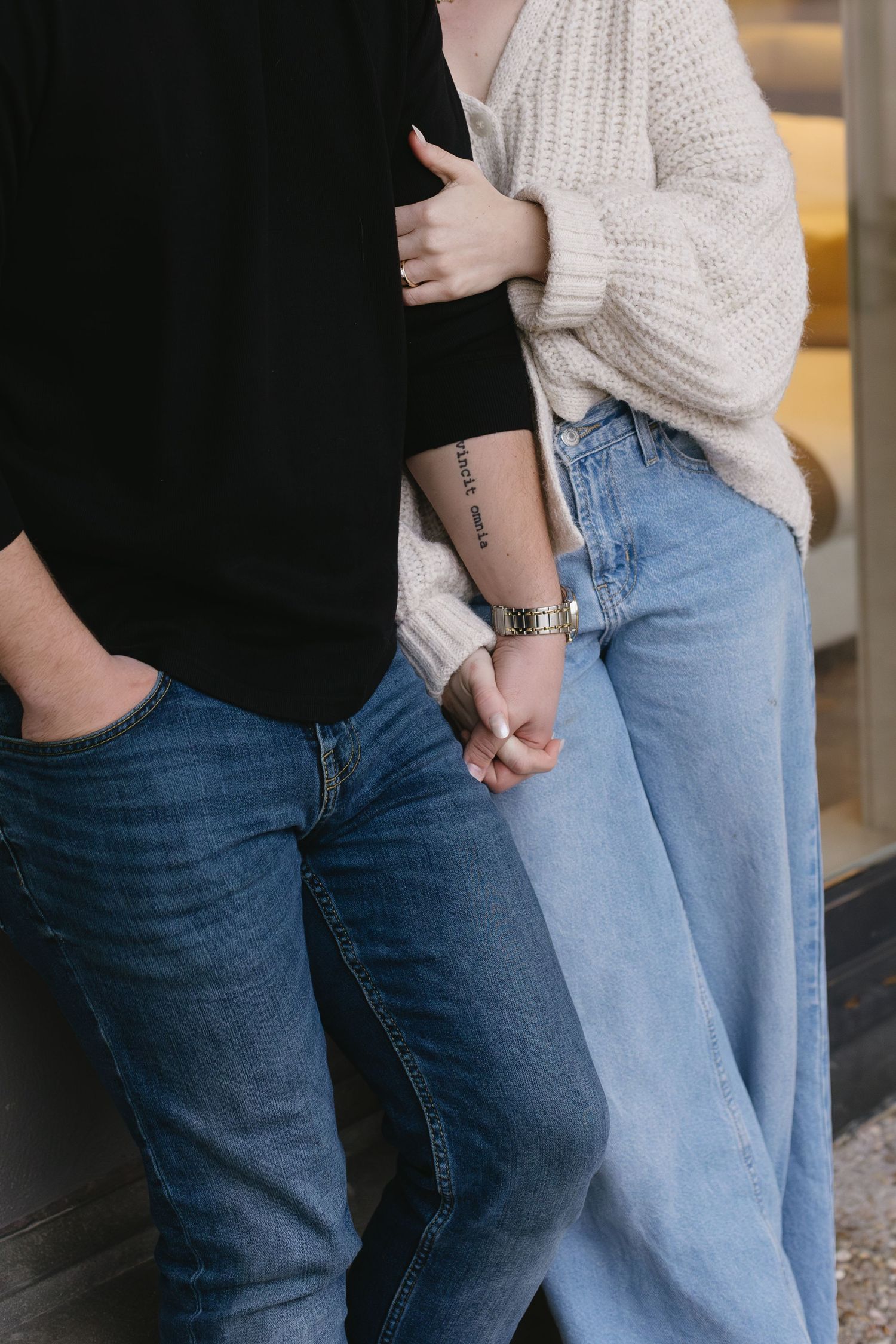 Close-up shot of two people standing side by side wearing jeans and casual tops.
