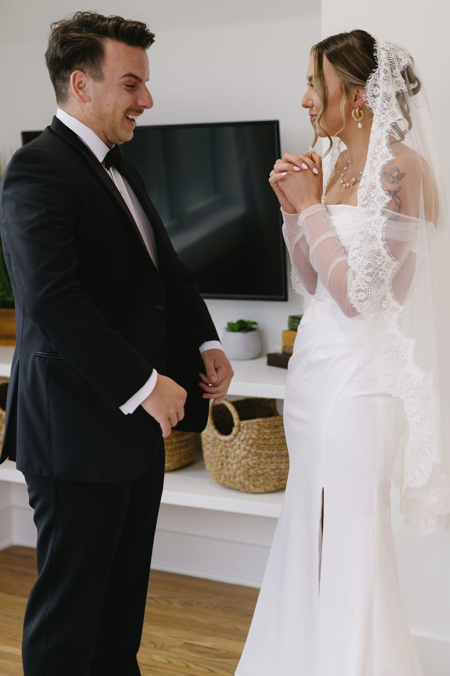 A couple shares a joyful moment on their wedding day, with the bride wearing a lace veil and white gown.