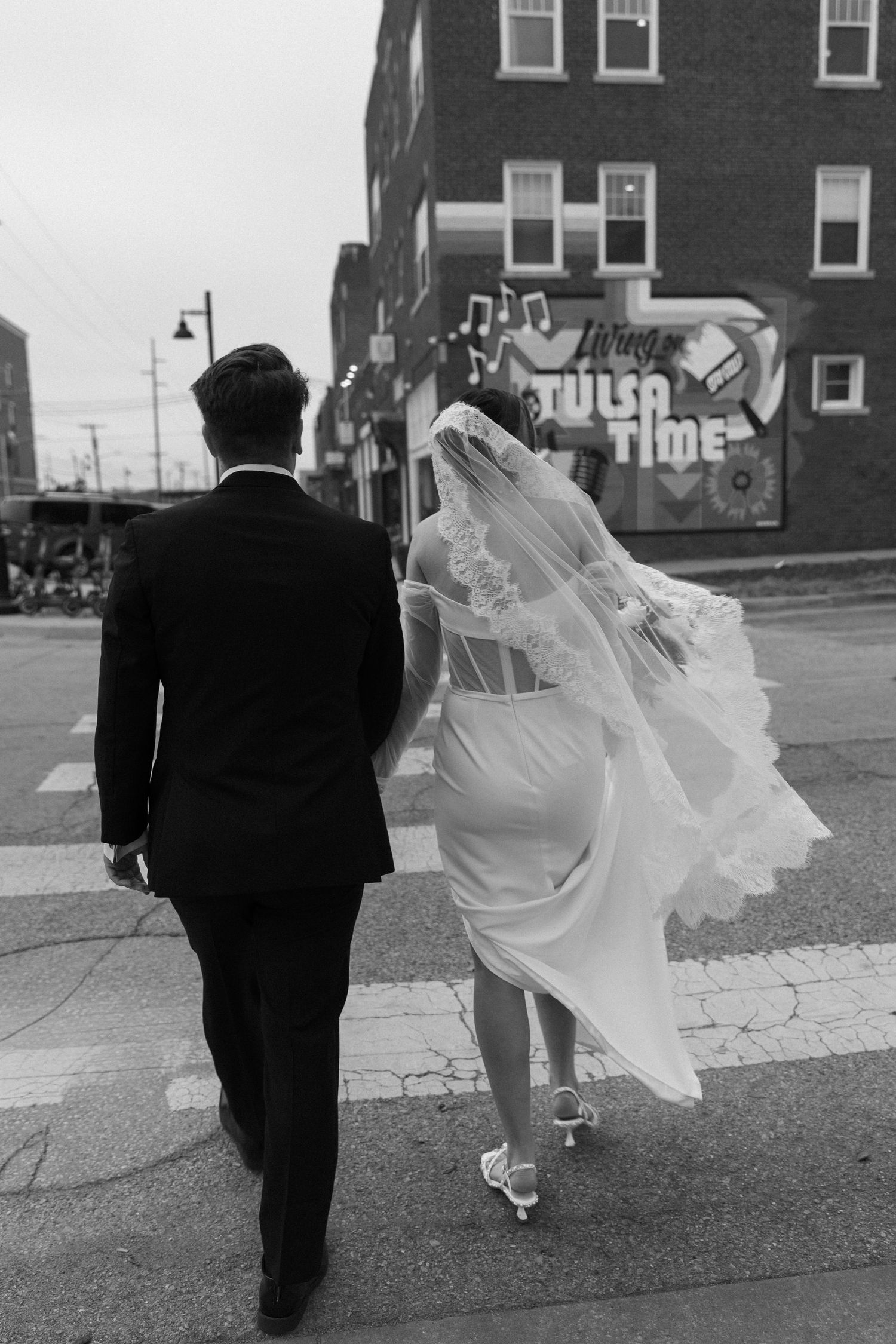Black and white wedding photo sequence showing couple walking together on sidewalk with bride's dress flowing.