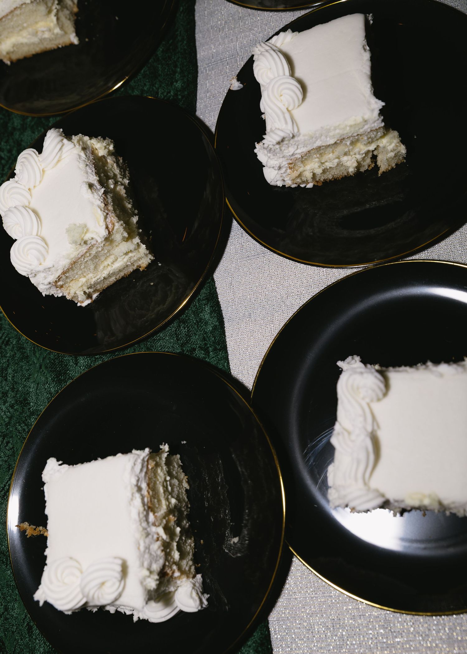 Black plates arranged in a row with dollops of white cream or frosting on each one.