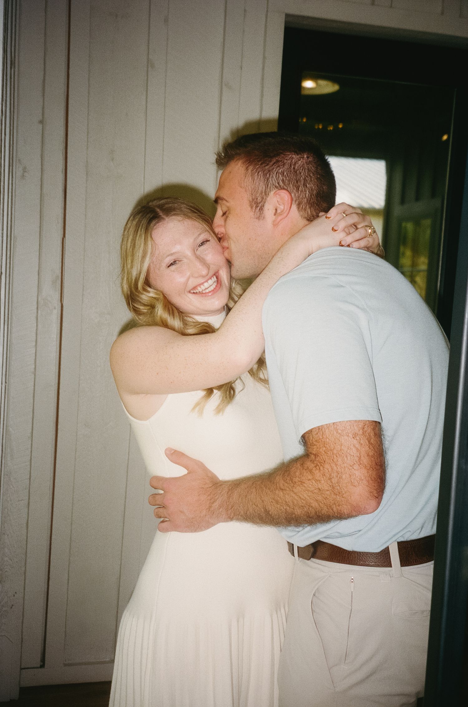A romantic couple embraces and dances together in a casual indoor setting, creating a series of candid moments.