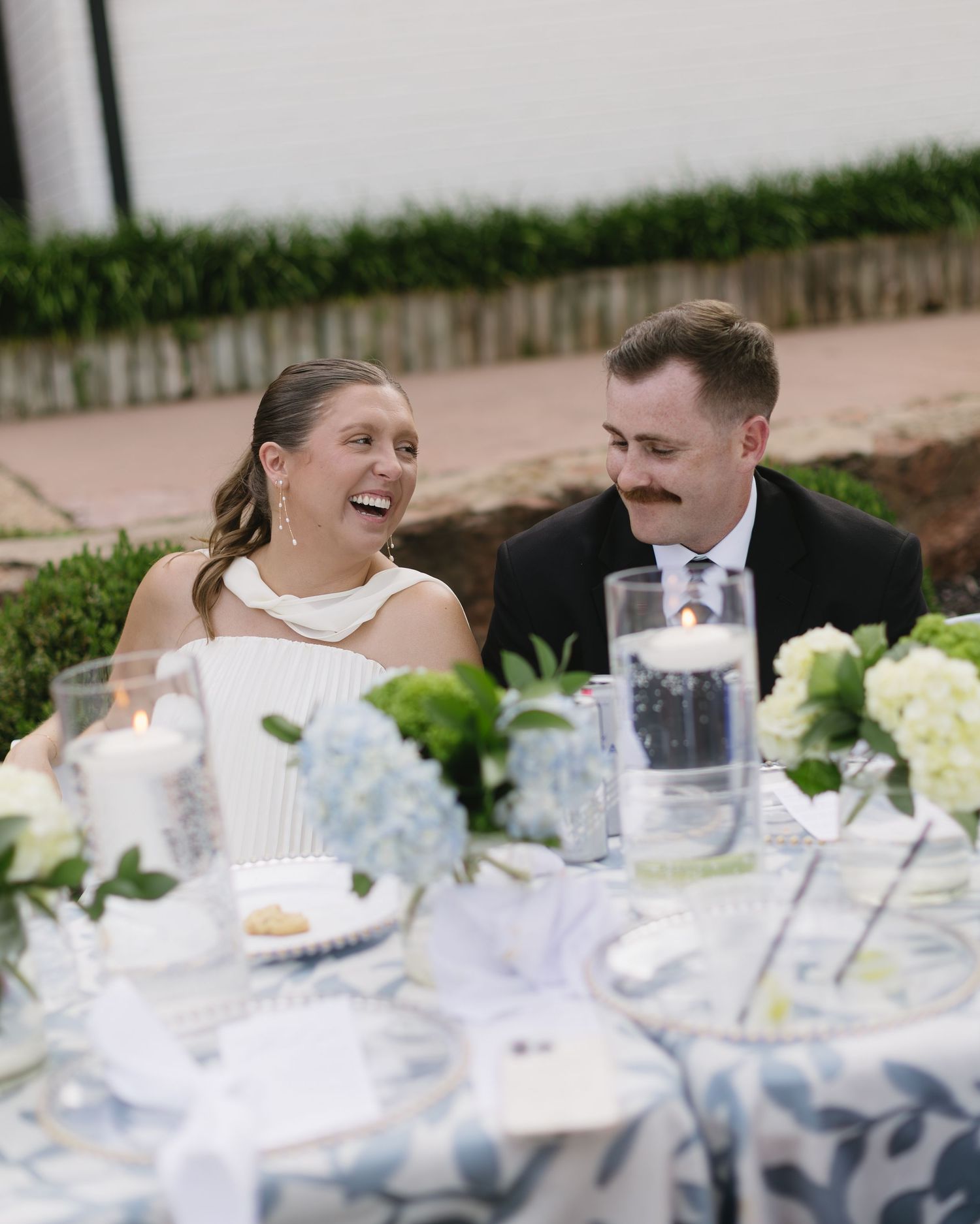 Joyful moment shared at wedding reception table with blue floral decor.
