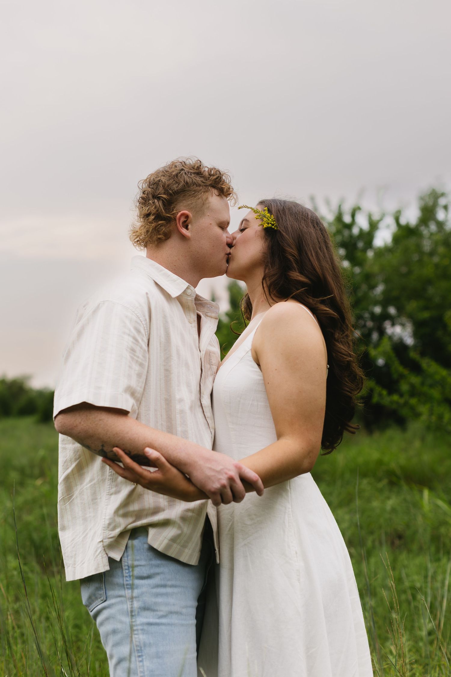 A romantic couple shares tender kisses in a green summer meadow.