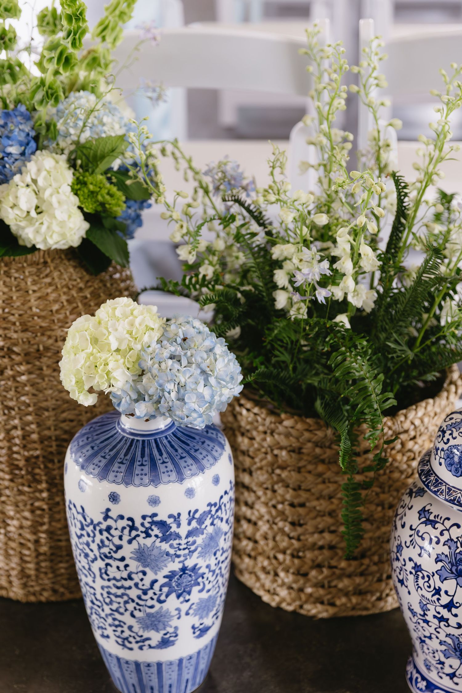 Delicate floral arrangements in blue and white chinoiserie vases alongside woven basket containers.