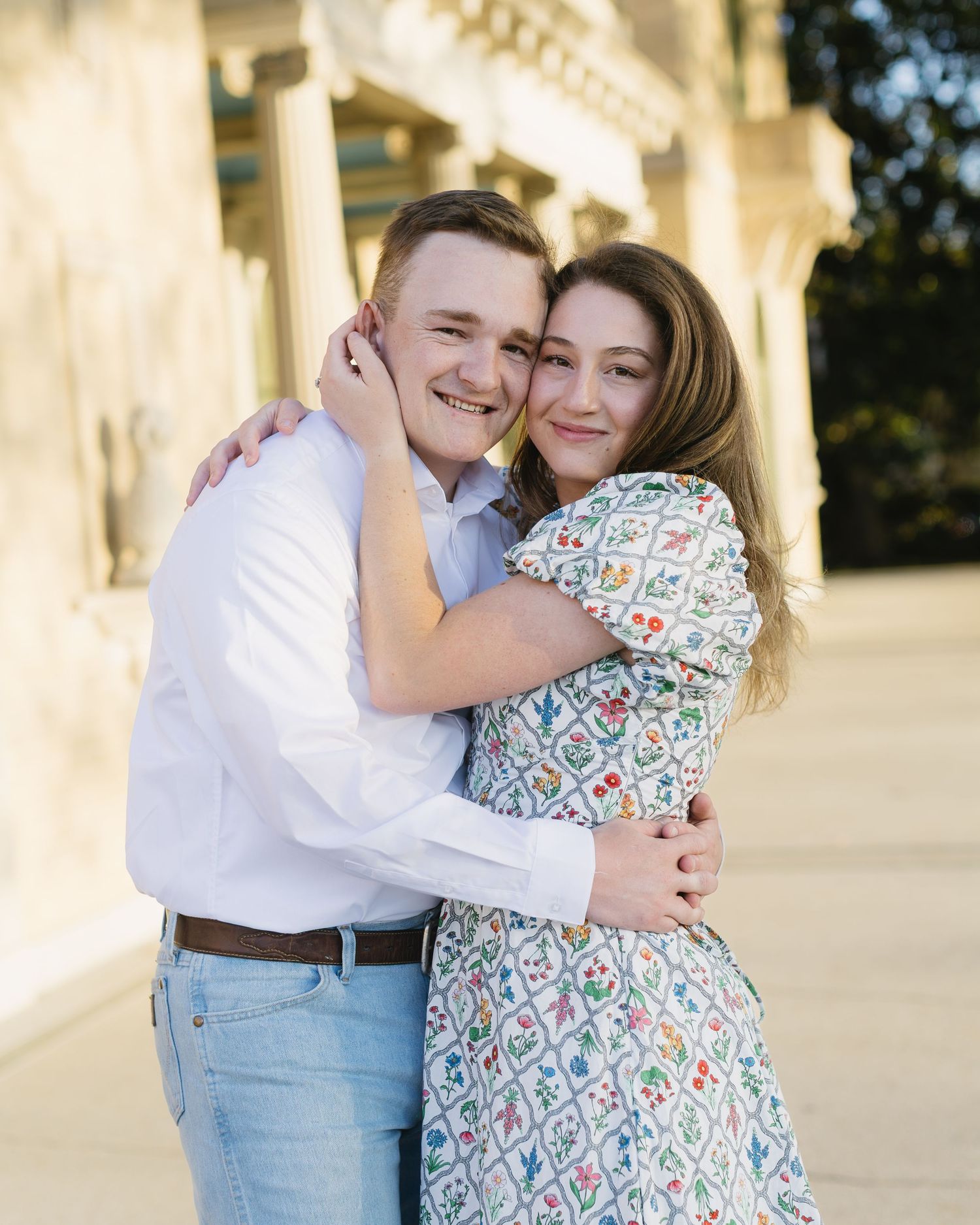 A couple shares joyful moments together in front of classic white architectural columns.