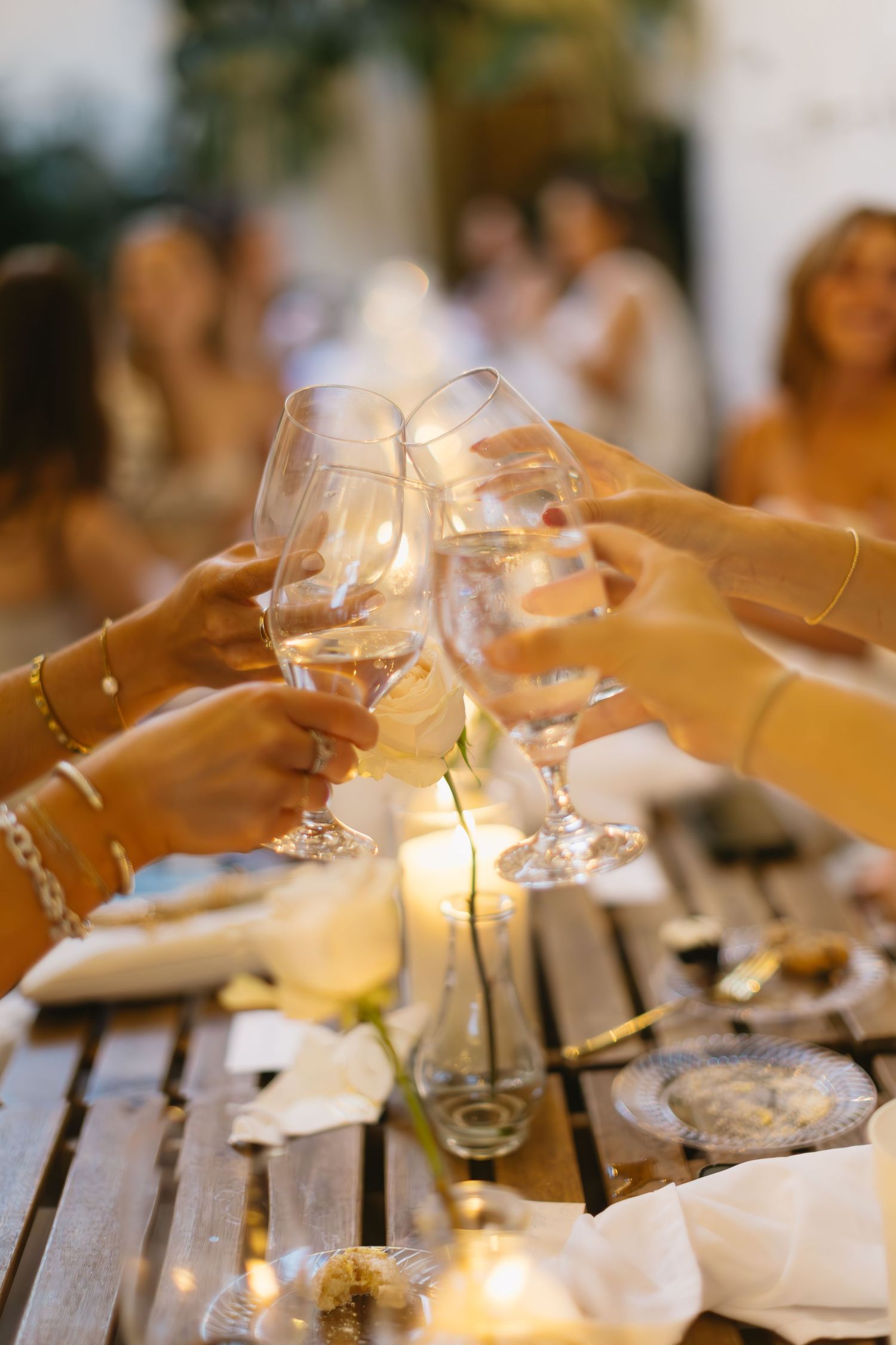 Wine glasses clink together over an elegantly set dining table with ambient lighting.