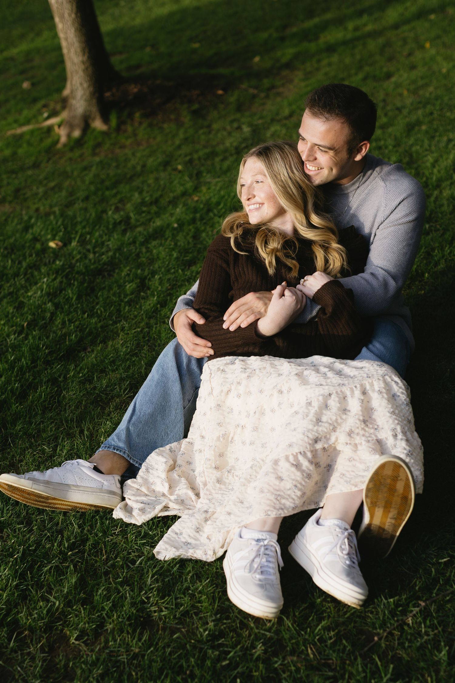 Couple relaxing on grass while looking at phone during casual outdoor session.
