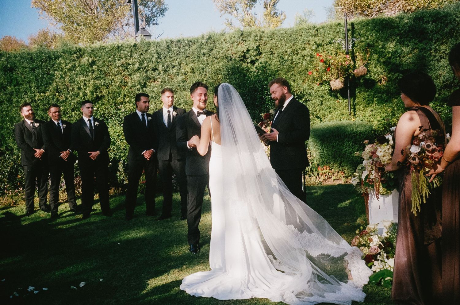 Outdoor wedding ceremony with guests seated in rows among autumn trees.