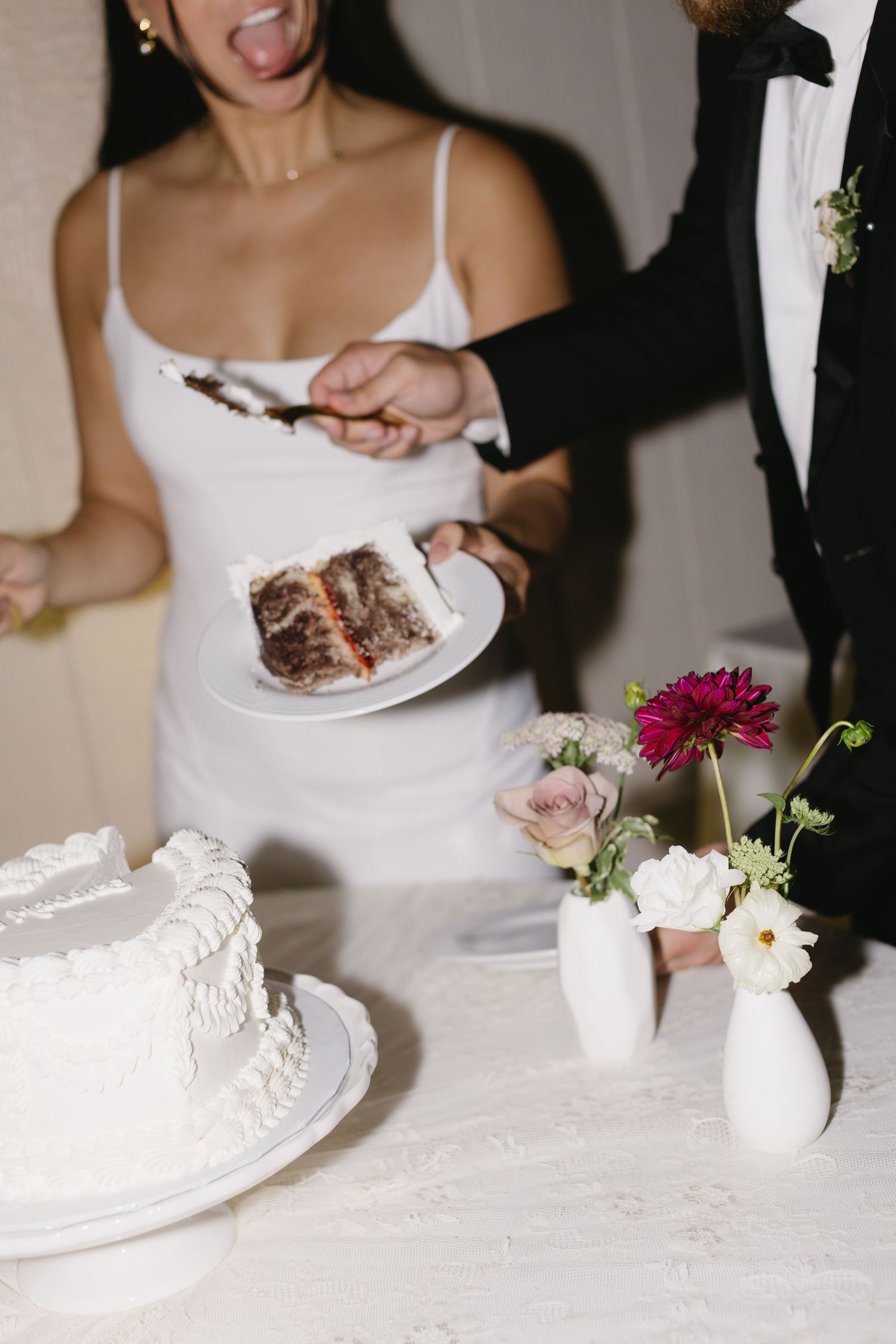 Wedding couple cutting and sharing their white wedding cake at the reception.