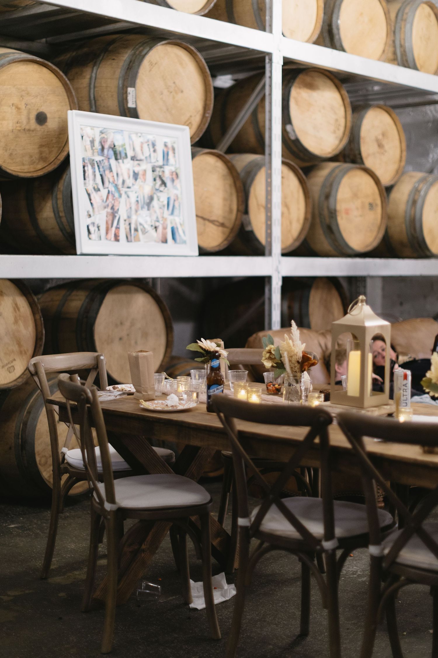 Wedding reception table setup in a rustic barrel room with wooden tables and chairs.