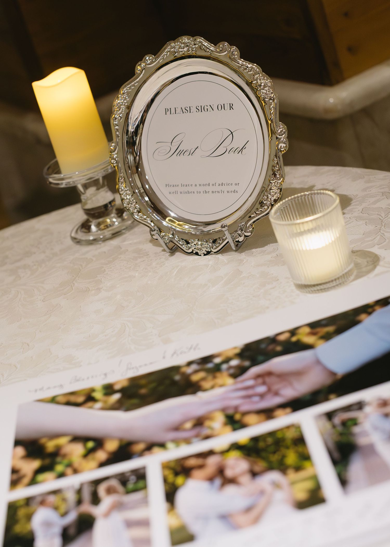 Wedding guestbook display with ornate silver frame and candles on white tablecloth.