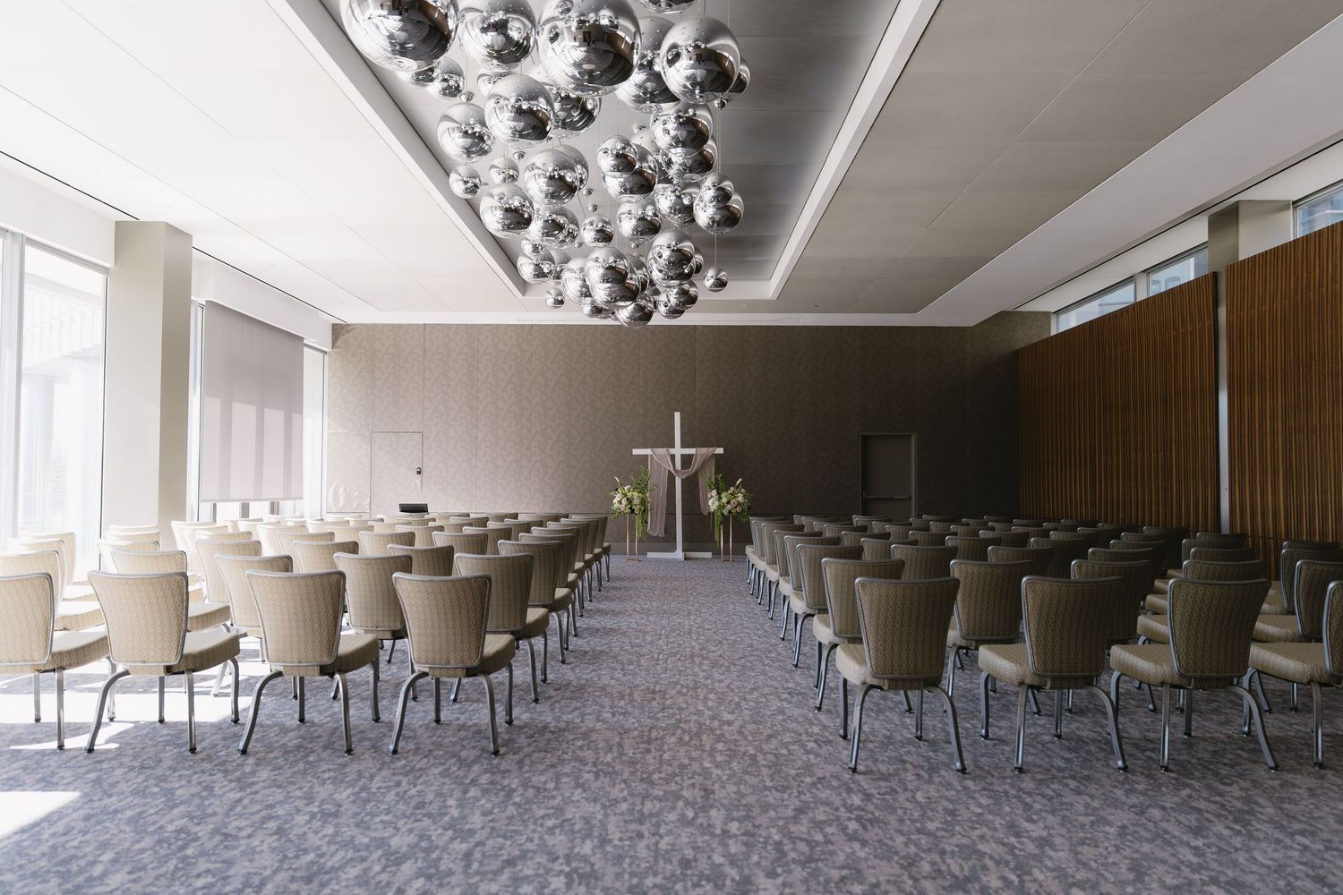 Modern church interior with geometric ceiling lights and rows of gray chairs.