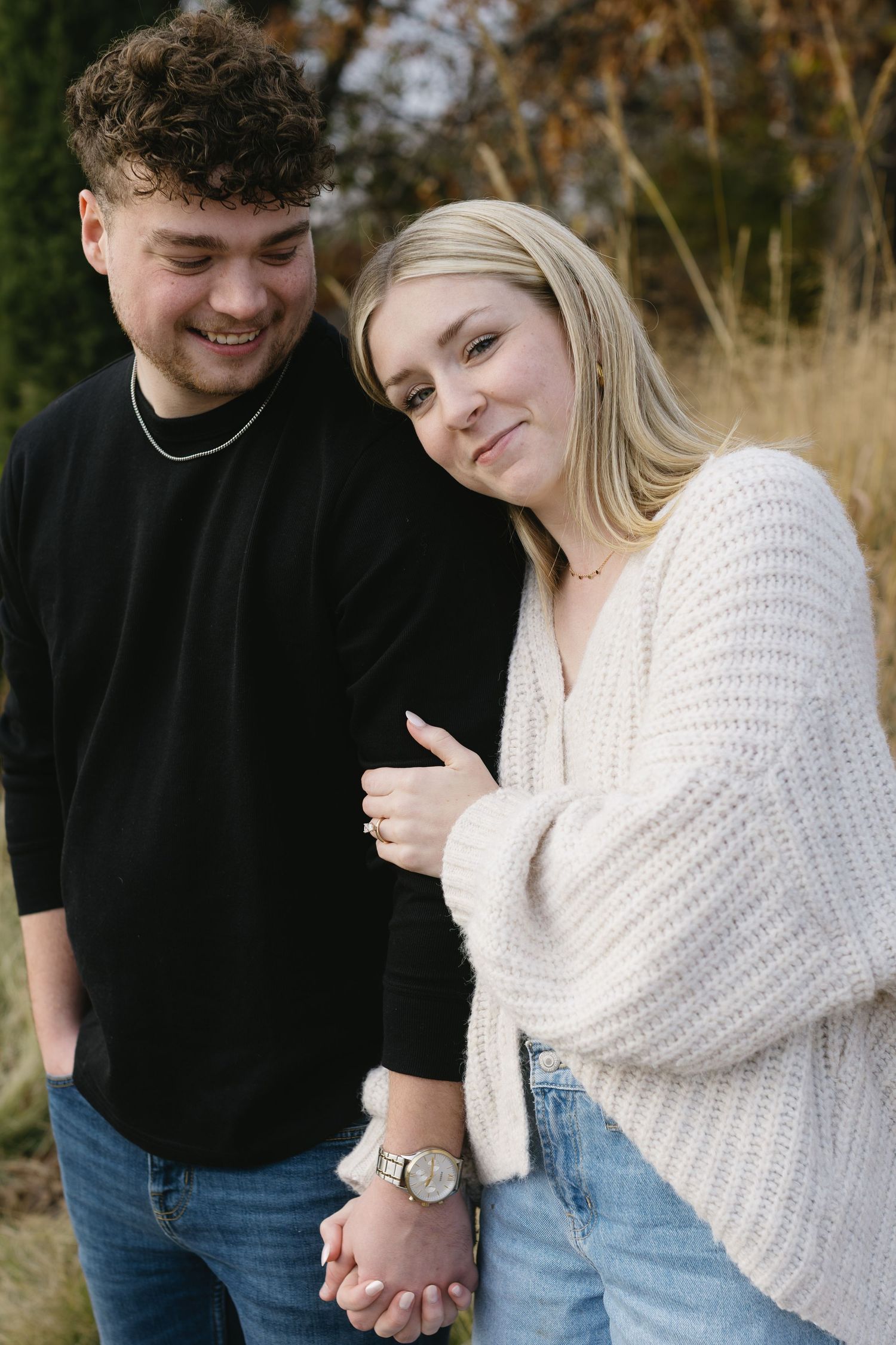 A couple shares a tender moment while wearing coordinating casual outfits outdoors.