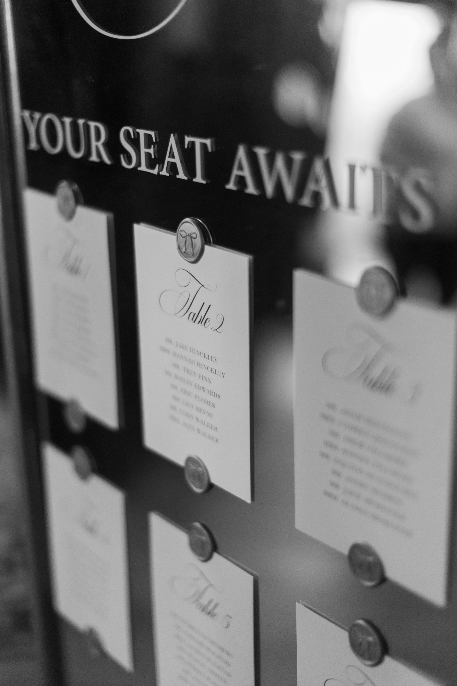Black and white close-up of elegant wedding seating cards arranged in a row.