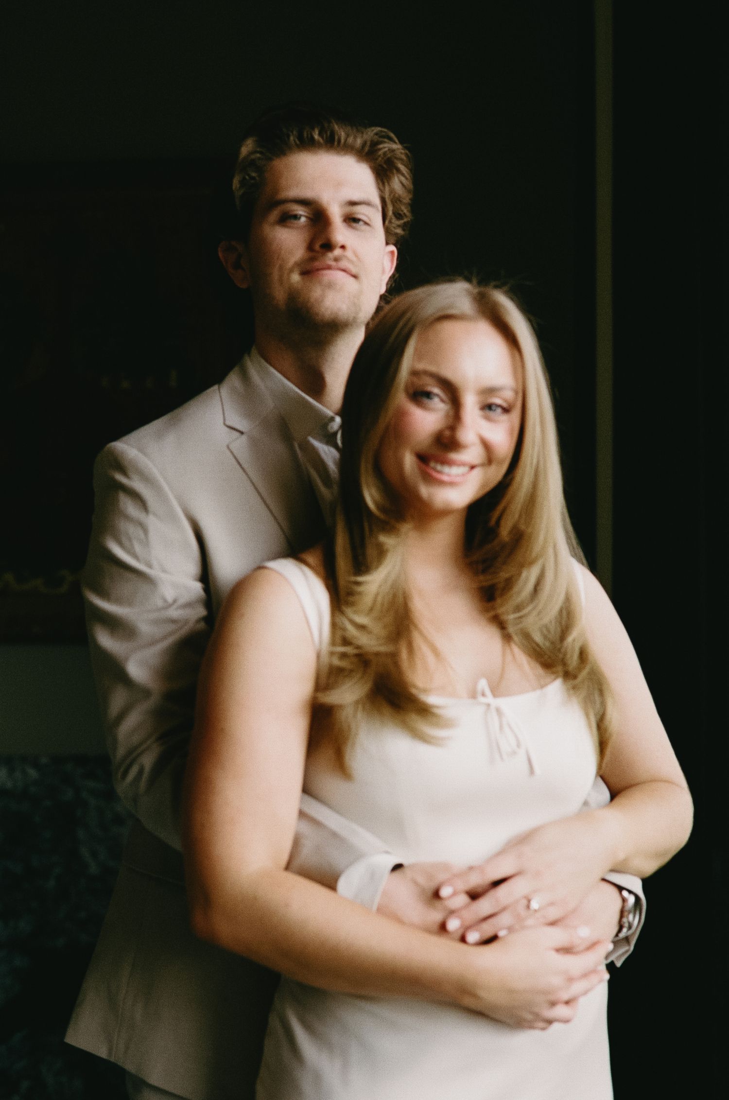 A couple in coordinated formal wear poses together for an intimate indoor portrait.