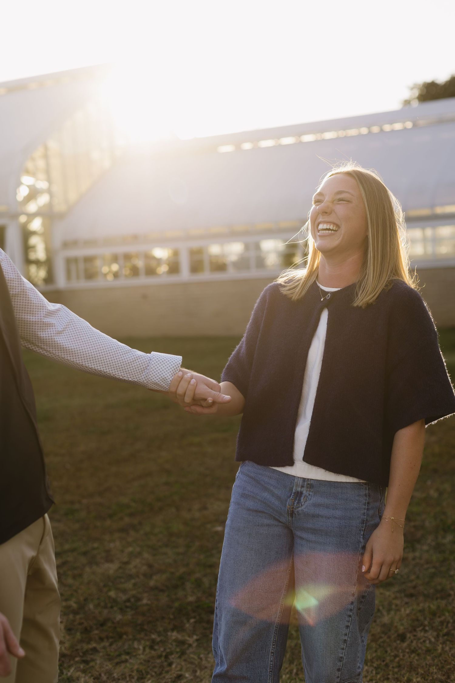 Joyful moment captured in sunlight as two people share laughter outdoors.