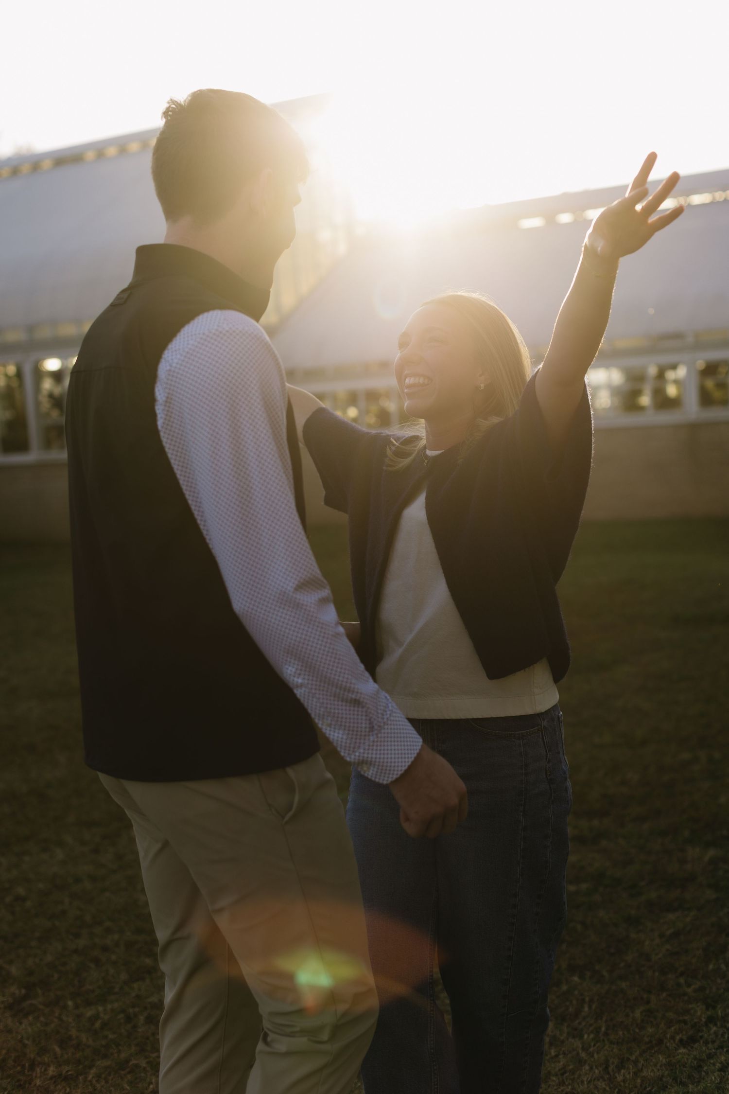 A couple shares a tender moment in golden sunlight on a grassy field.