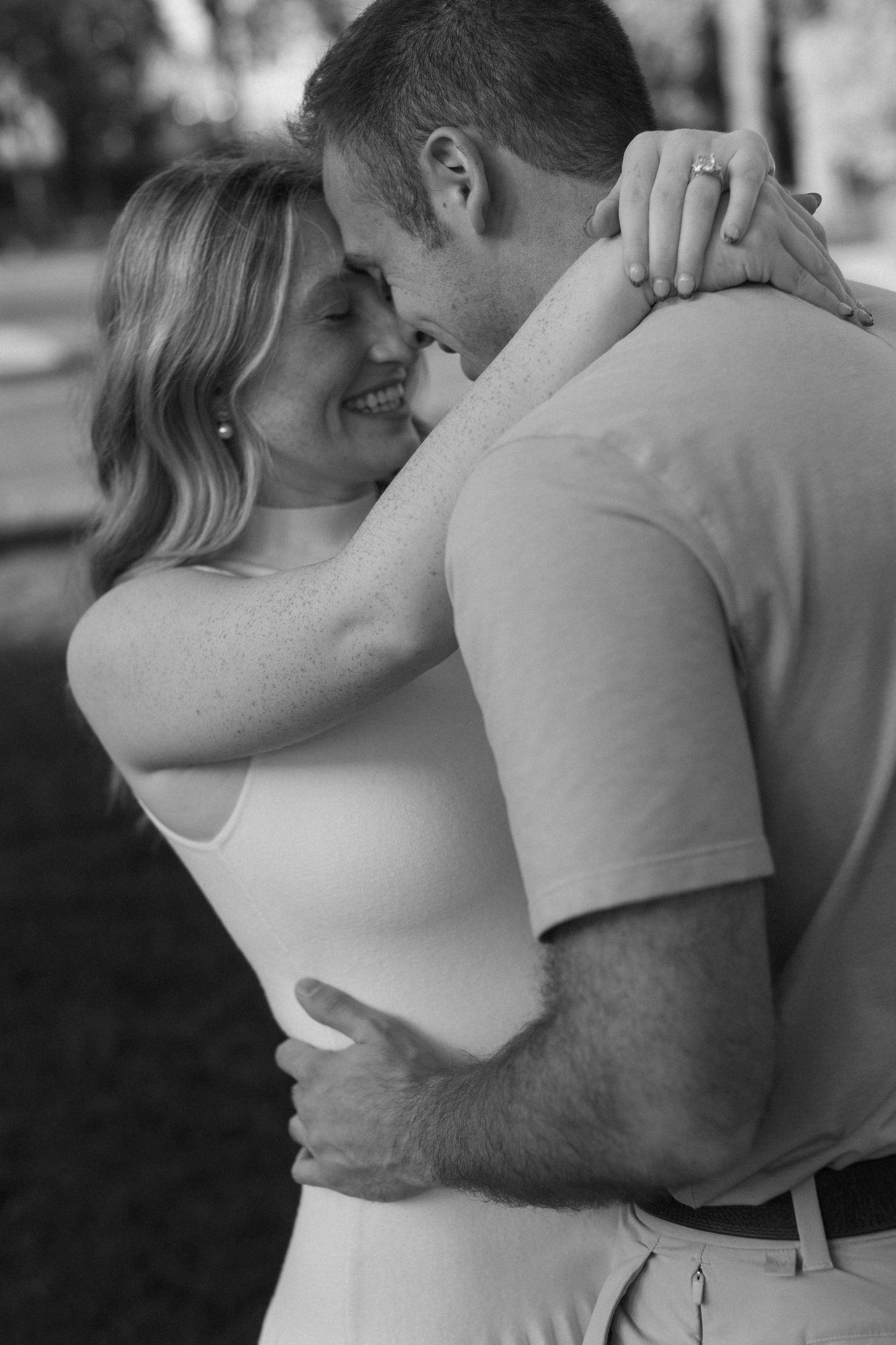 Black and white intimate portrait of a couple embracing in casual attire.