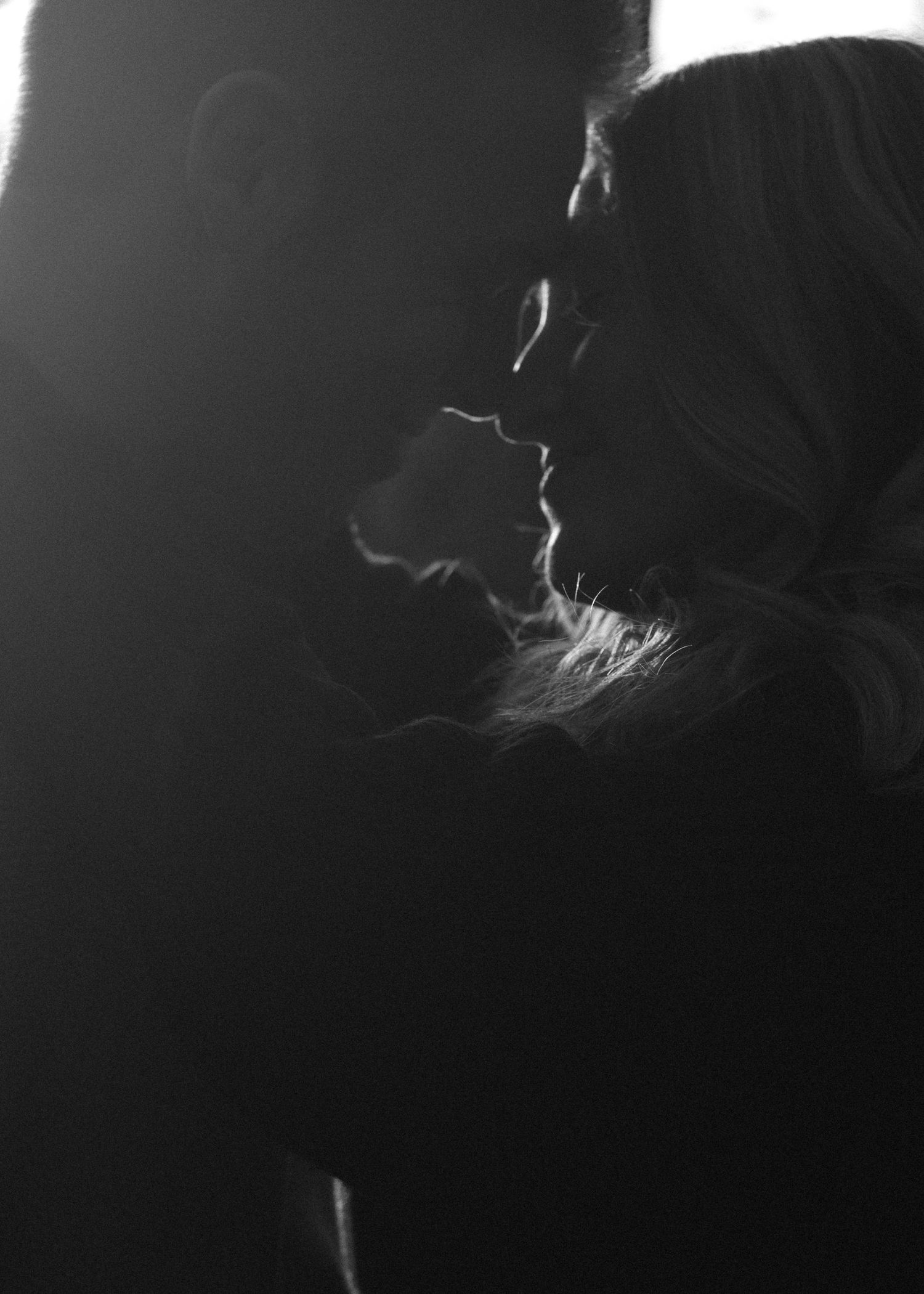 A silhouetted couple in an intimate moment against a dark background.