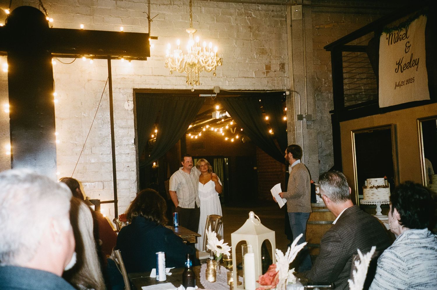 Dimly lit indoor venue with guests mingling during an evening celebration.