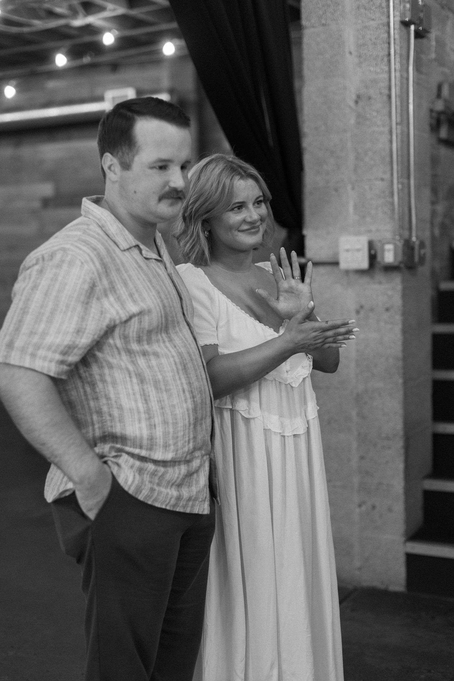 Black and white photo of a couple posing together in a rustic indoor setting.