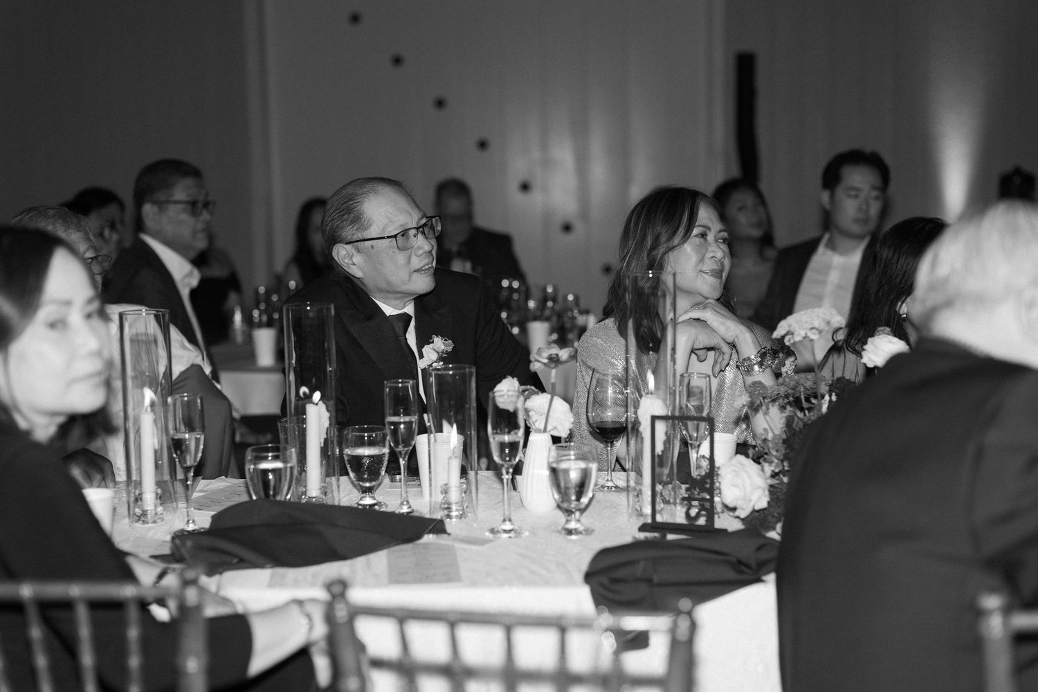 Black and white reception scene with tables and ambient lighting.
