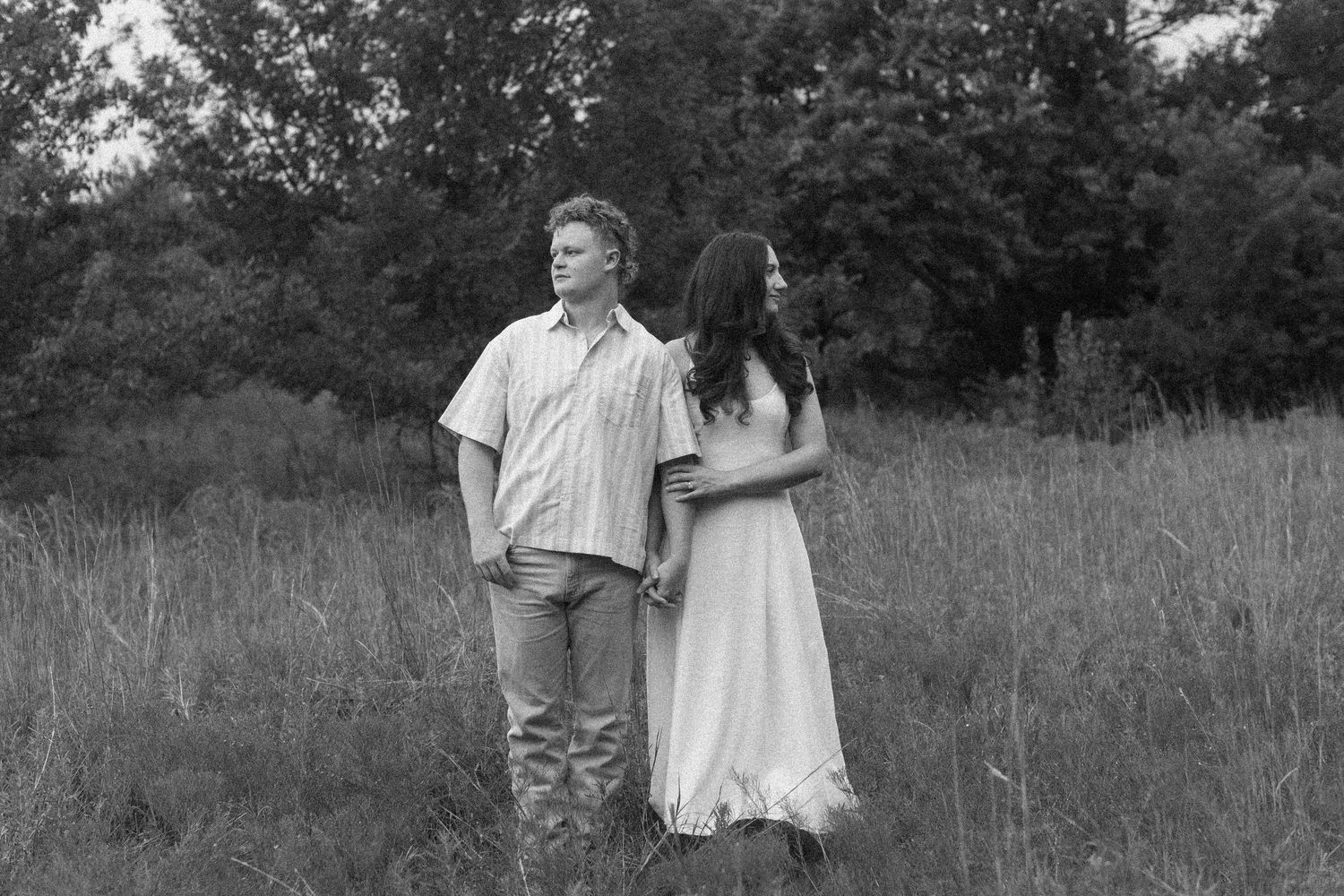 A black and white film strip showing figures walking together in a grassy field.