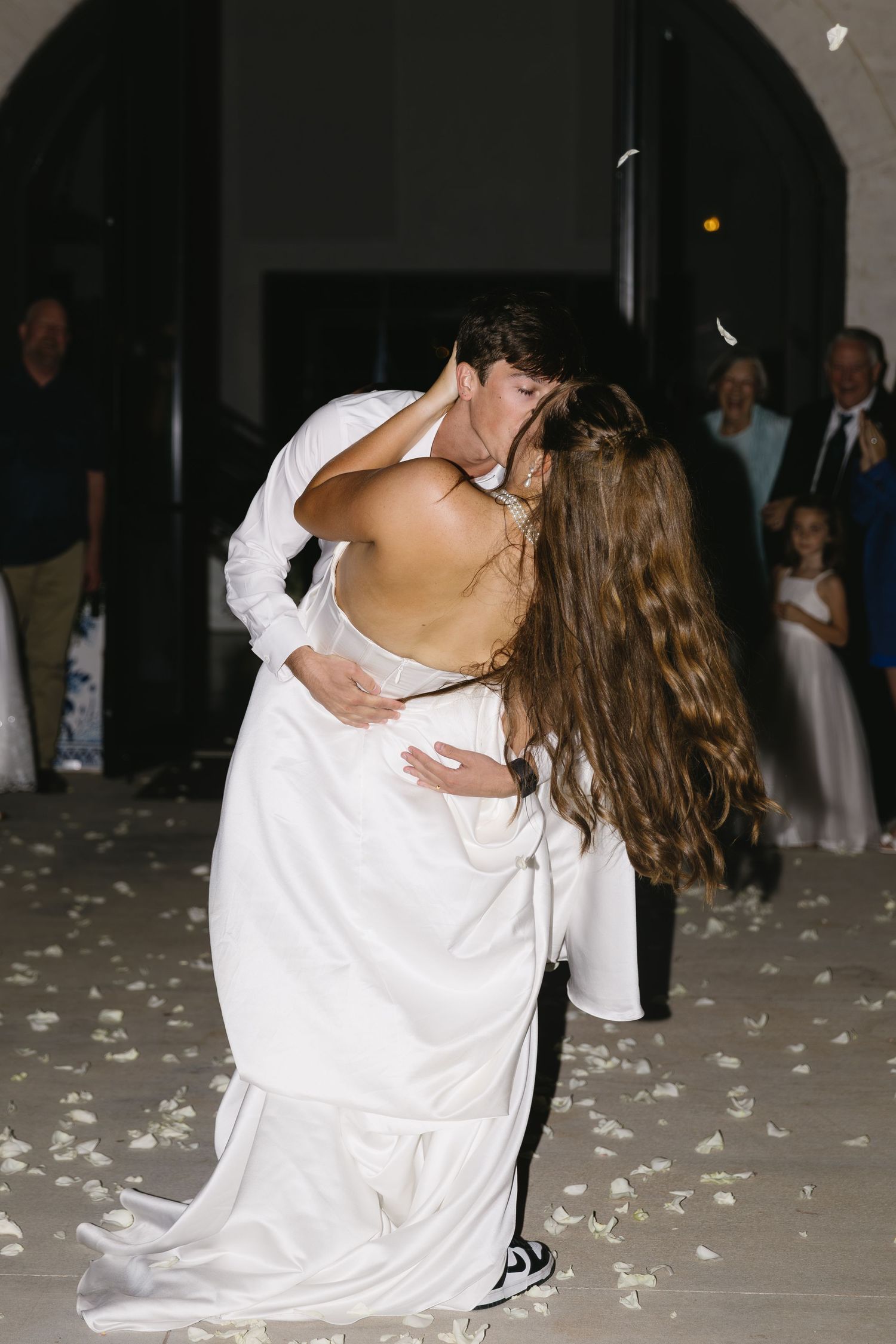 Wedding couple's first dance surrounded by rose petals on dance floor.