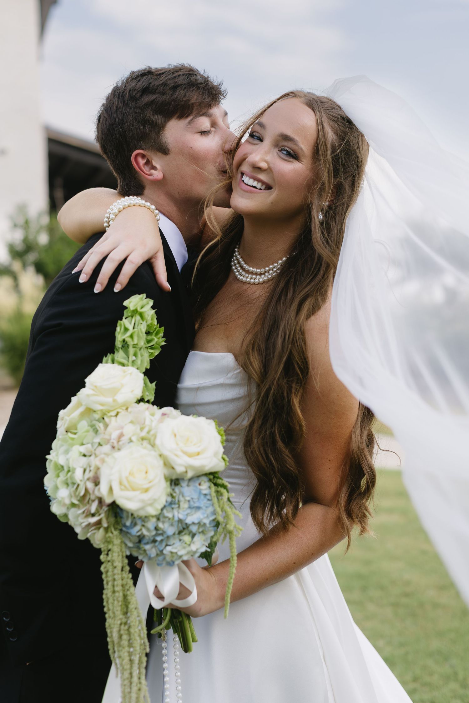 Beautiful wedding portrait with bride holding white and blue hydrangea bouquet.