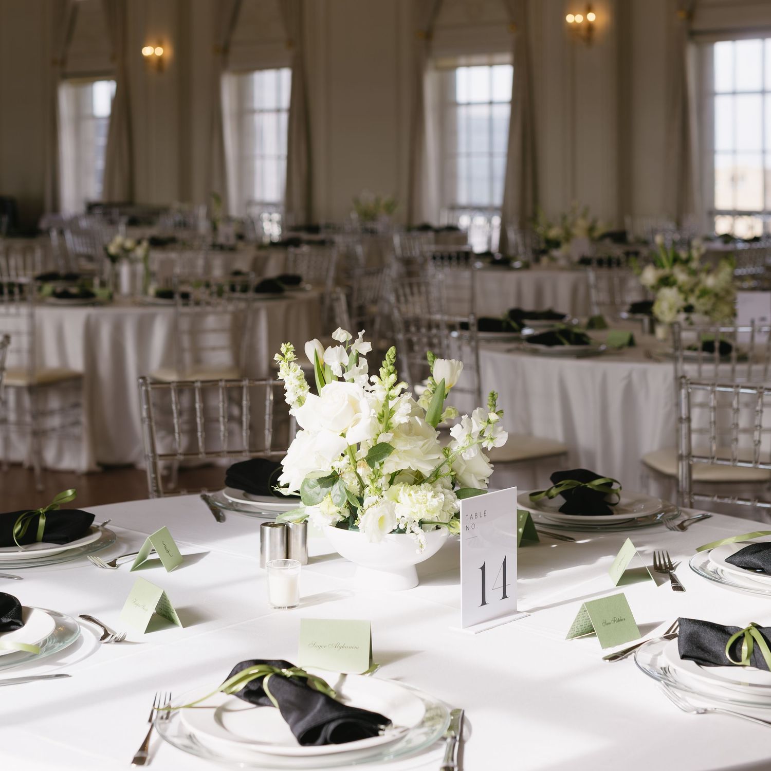 Elegant wedding reception tables with white linens, floral centerpieces and formal place settings.