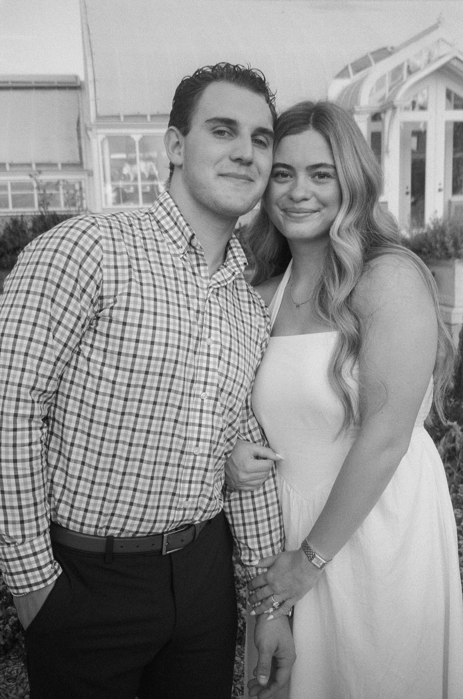 A couple poses together for a series of casual outdoor portraits in black and white.