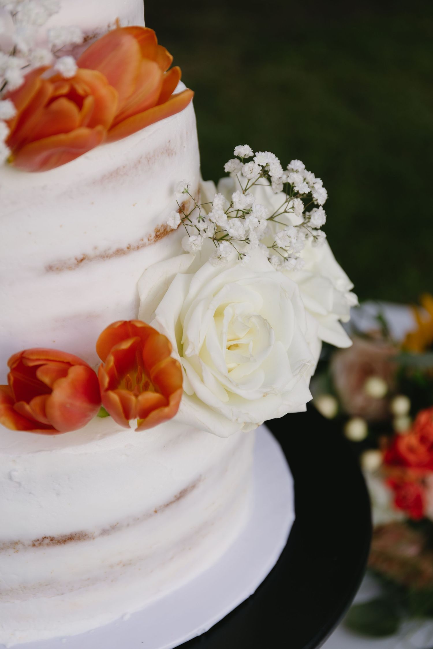 White wedding cake decorated with coral and white flowers in semi-naked style.